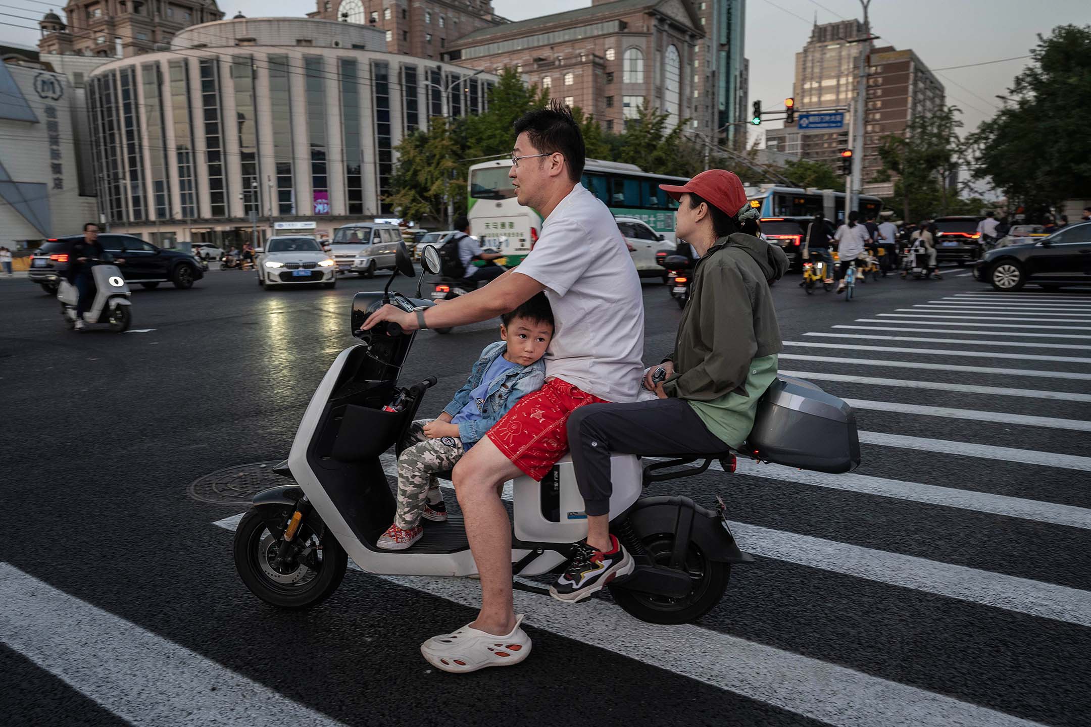 2023年9月13日,中國北京,一家人騎著摩托車在馬路旁邊等待。攝: Kevin Frayer/Getty Images