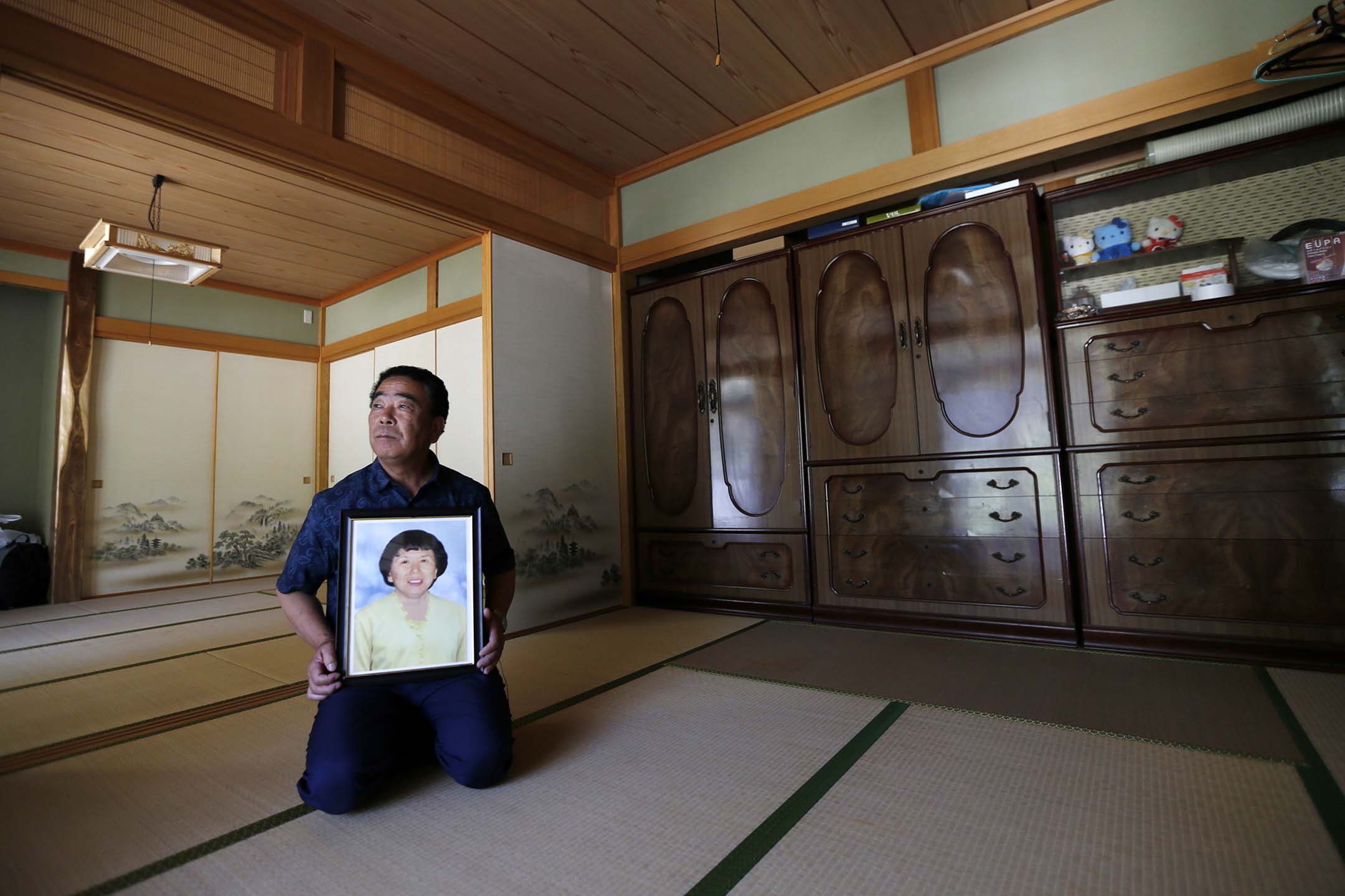 2014年6月23日,一名倖存者在福島縣川俁鎮山木屋區的家中舉著已故妻子的肖像。攝:Issei Kato/Reuters/達志影像