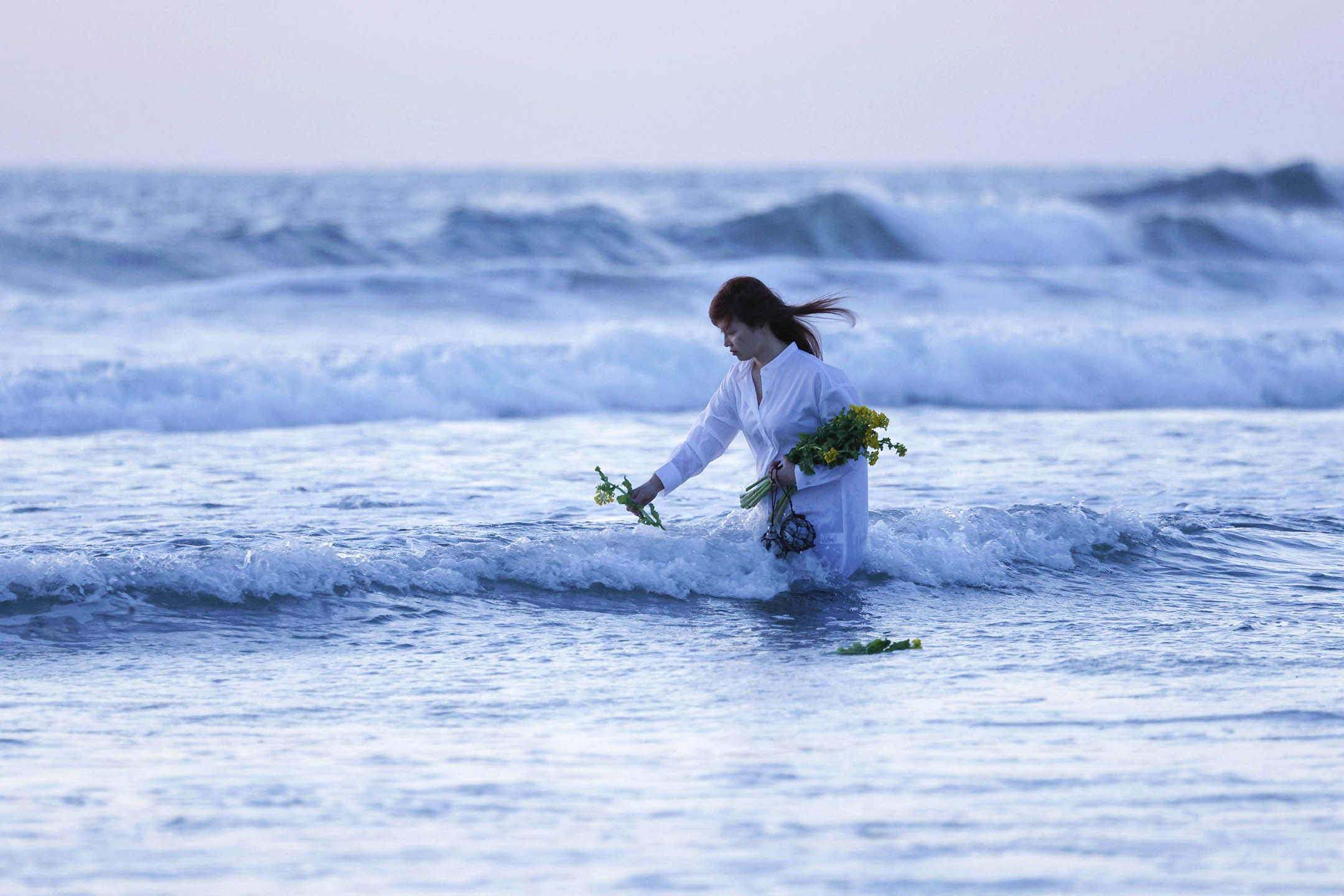 2023年3月11日,福島縣磐城市的海灘上,一名婦女在311地震的災區獻花,哀悼死者。攝: Kyodo via Reuters/達志影像