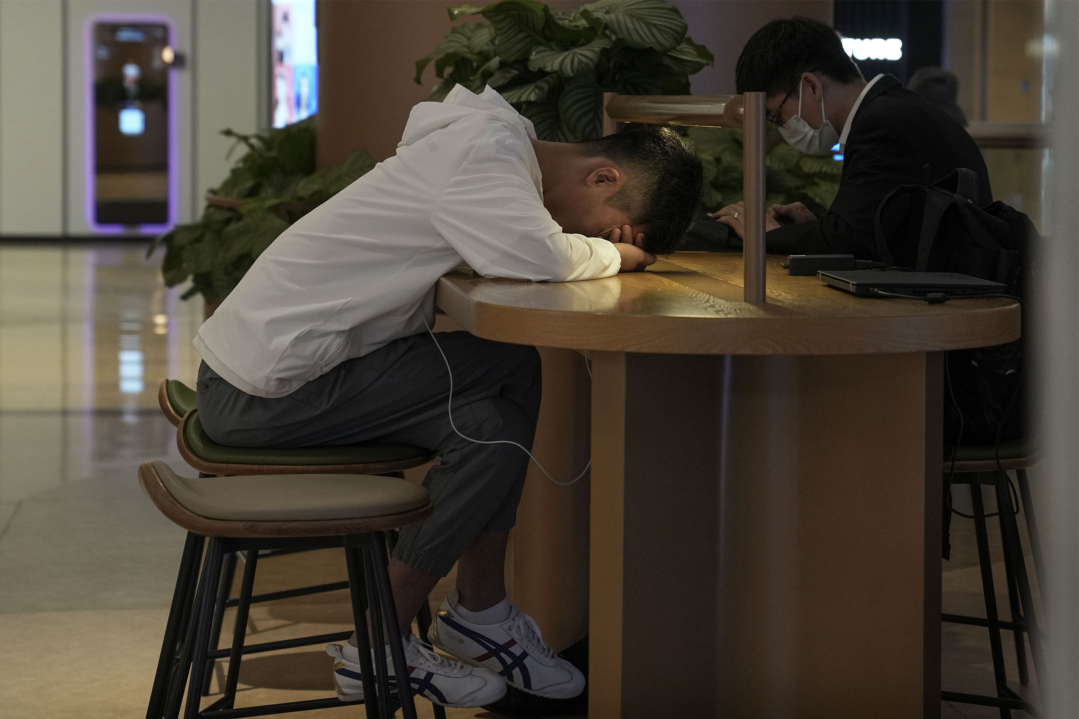 2023年5月24日,北京一家購物中心内的咖啡館,一名男子在小憩。攝:Andy Wong/AP/達志影像