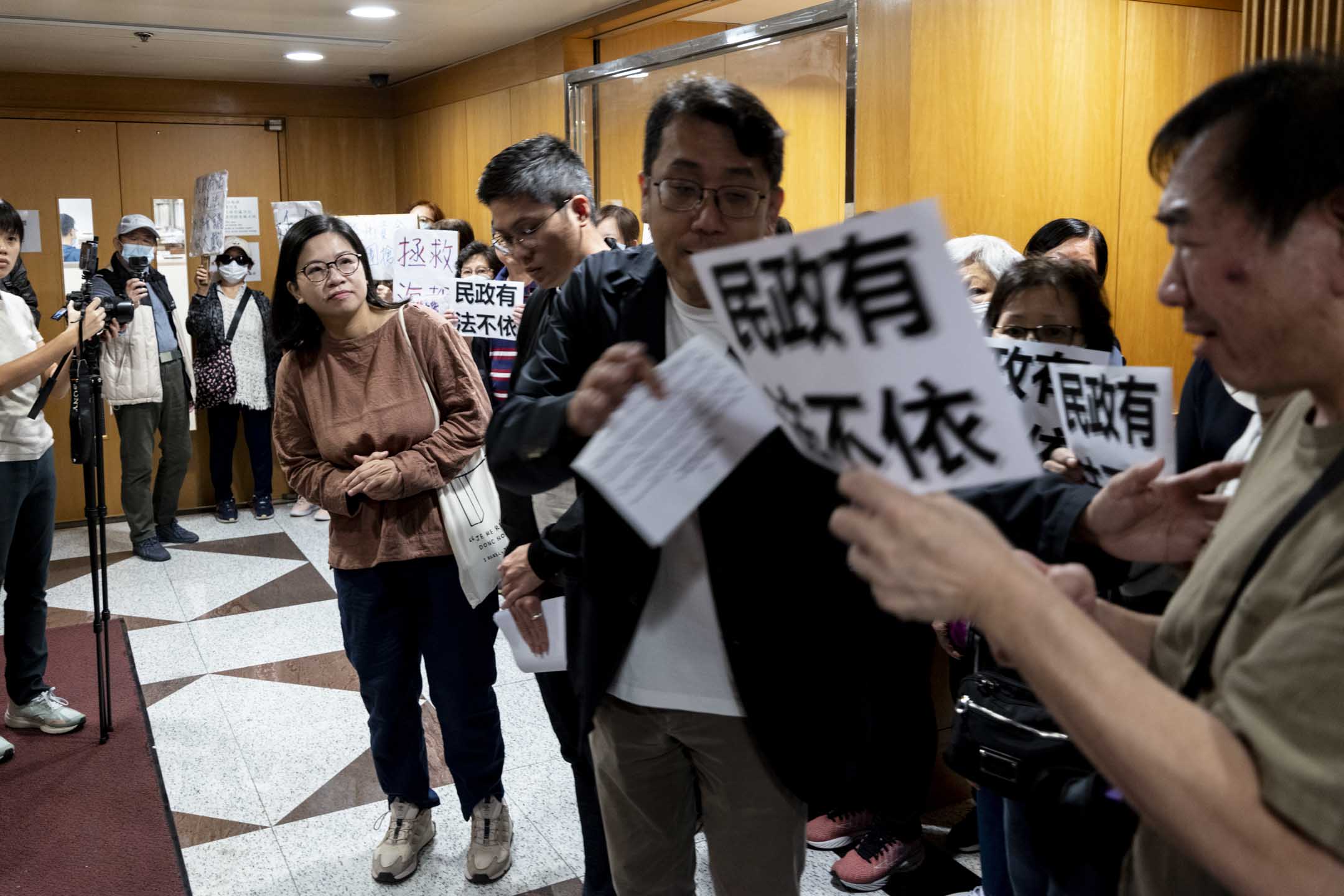 反圍標大聯盟發言人莊榮輝、伍凱欣與數十名海都樓業主到民政署進行抗議。攝:林振東/端傳媒