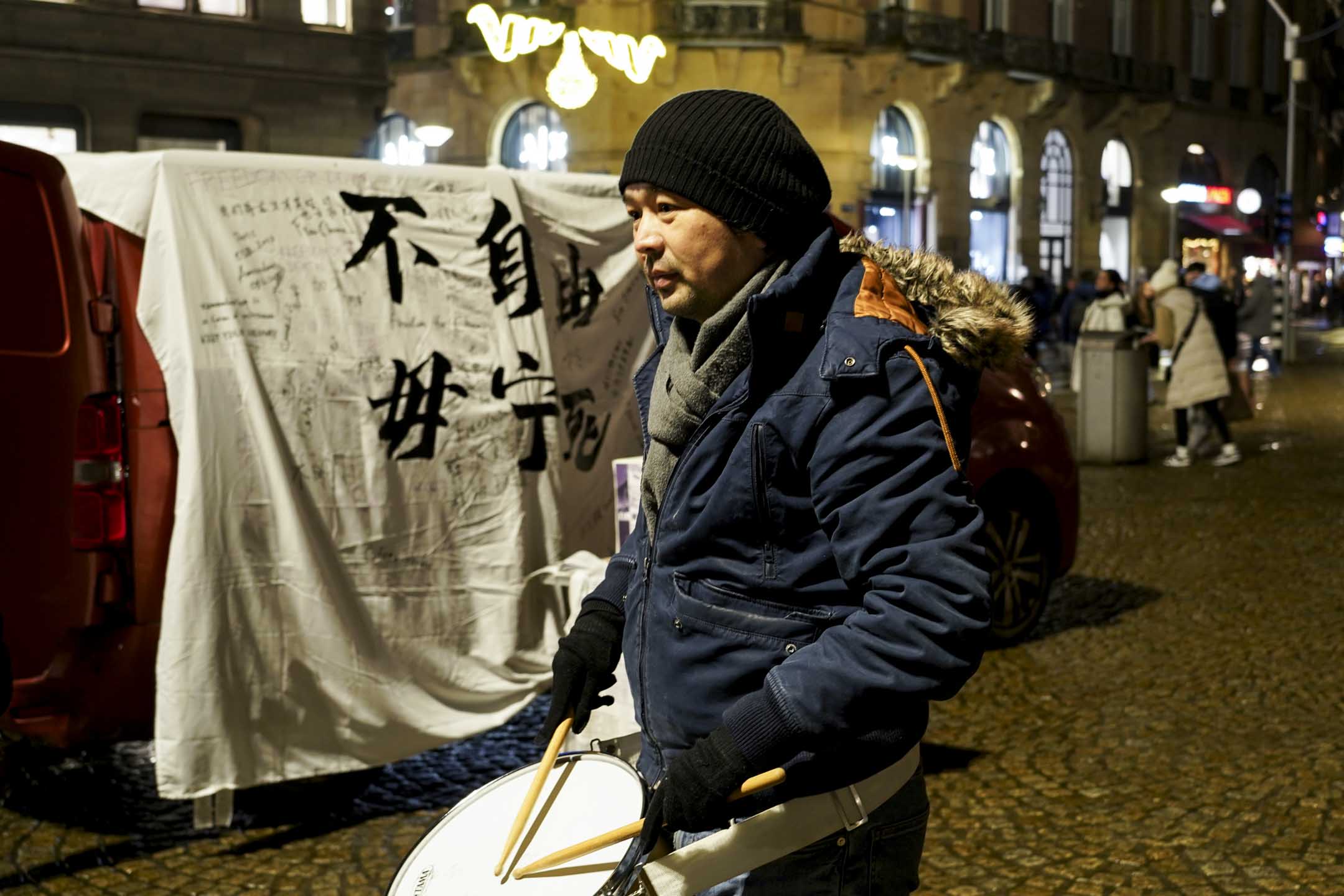 巴黎「自由廣場」的哈薩克族裔成員米爾。12月8日晚上六點多,他在冷風中敲起鼓,為唱歌的女生伴奏。攝影:林語婕