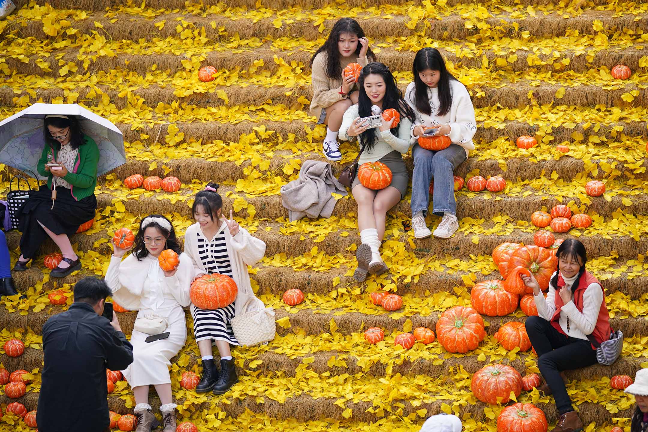 2023年11月20日,中國昆明,人們在購物中心用塑膠銀杏葉和塑膠南瓜裝飾的樓梯上拍照。攝:Liu Ranyang/China News Service/VCG via Getty Images