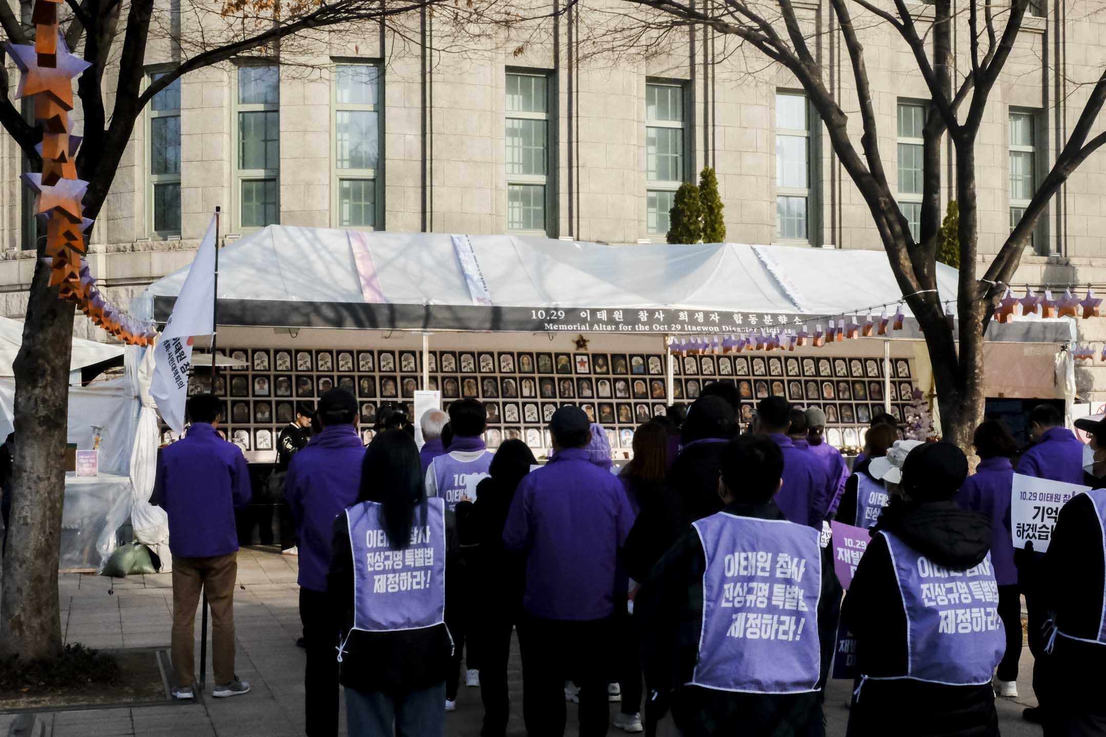 2023年12月8日下午,遺屬團體舉辦遊行促請國會通過特別法;行前,眾人對159名受害者遺像默哀。攝:余美霞/端傳媒