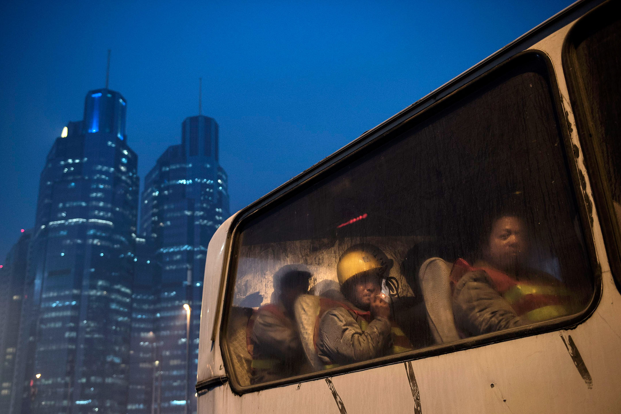 2014年12月9日,中国北京,建筑工人下班后乘坐公车离开。摄:Kevin Frayer/Getty Images