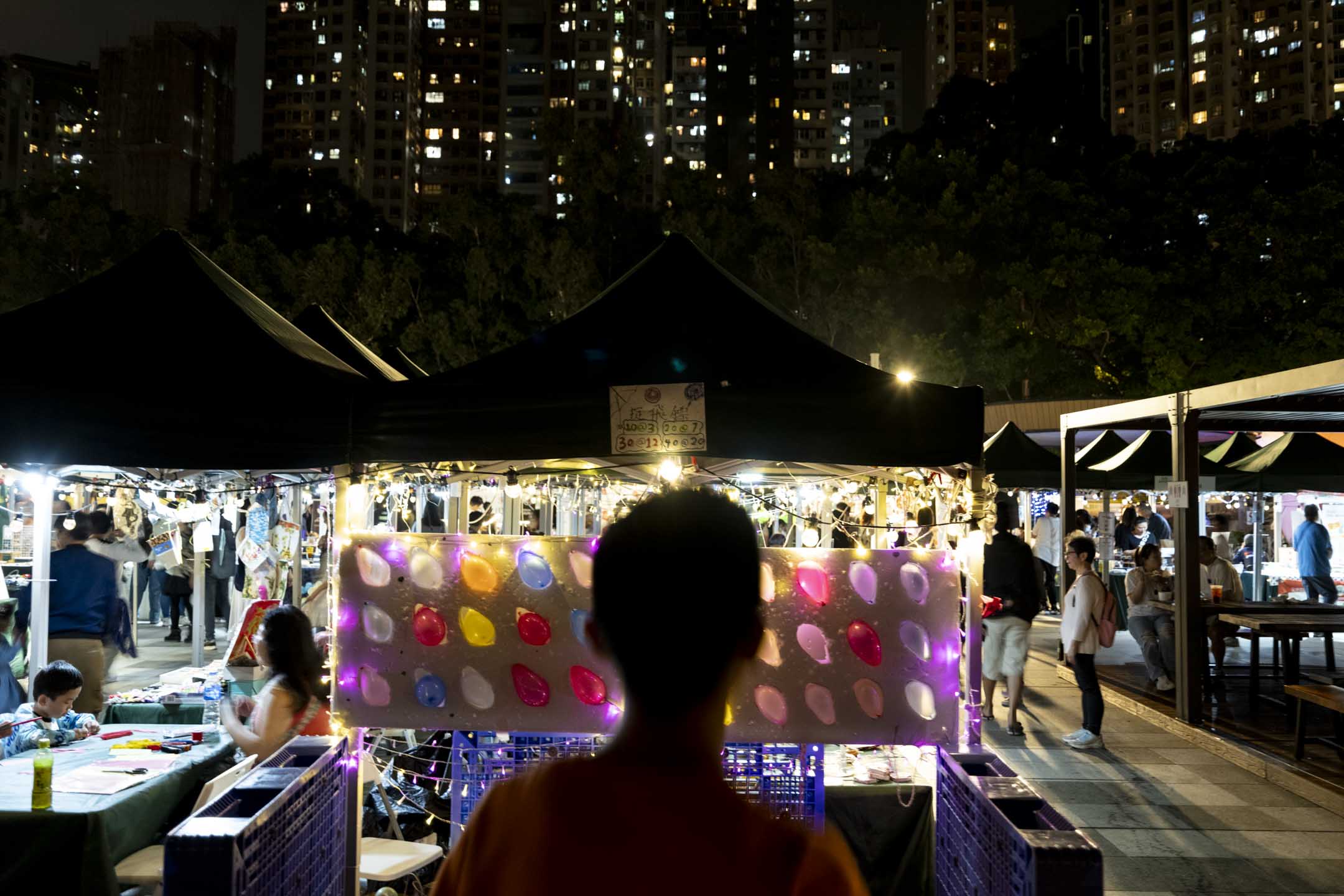 香港一名少年站在夜市中。摄:林振东/端传媒