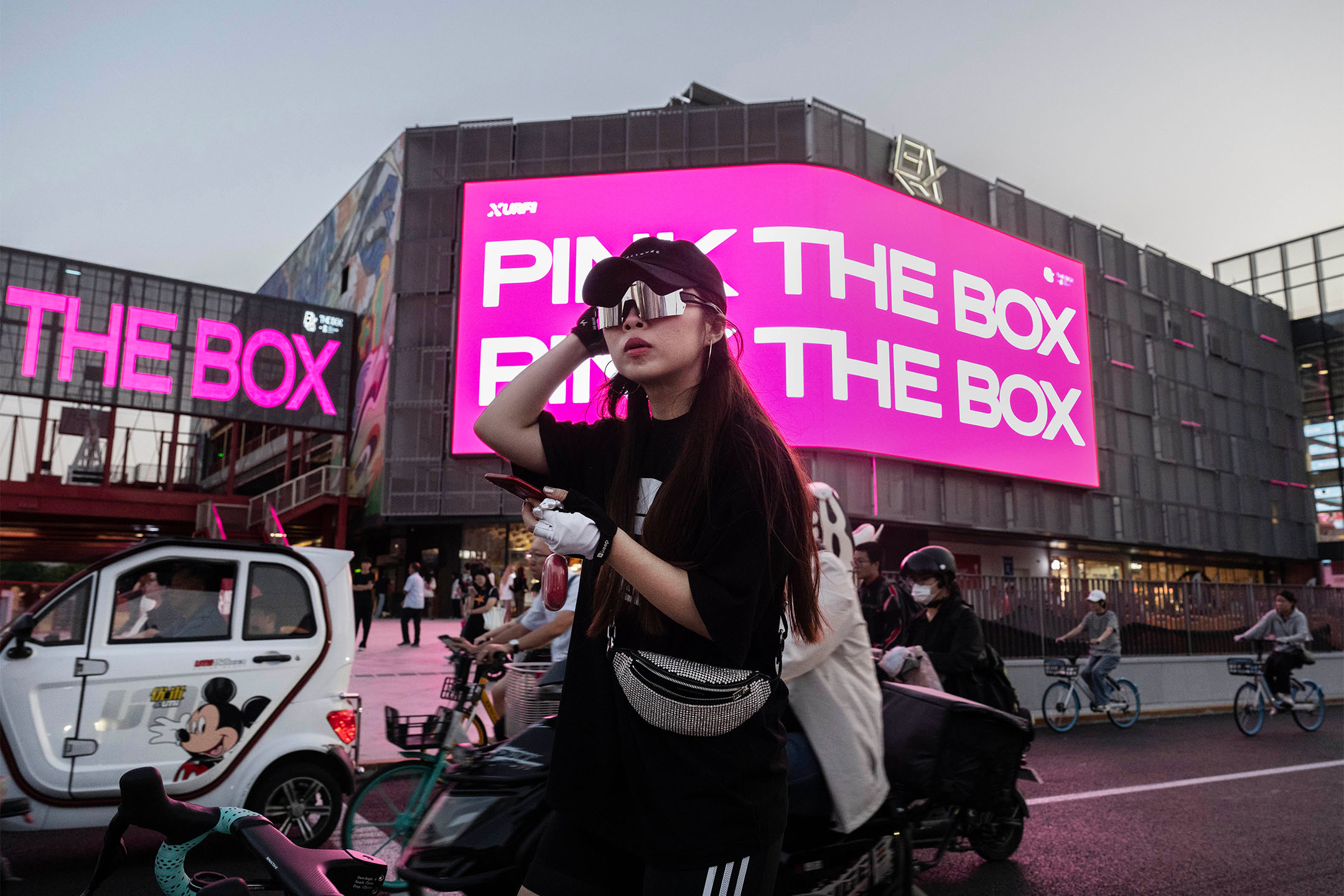 2023年9月13日,中国北京,一名女子骑著自行车等待过马路。摄:Kevin Frayer/Getty Images
