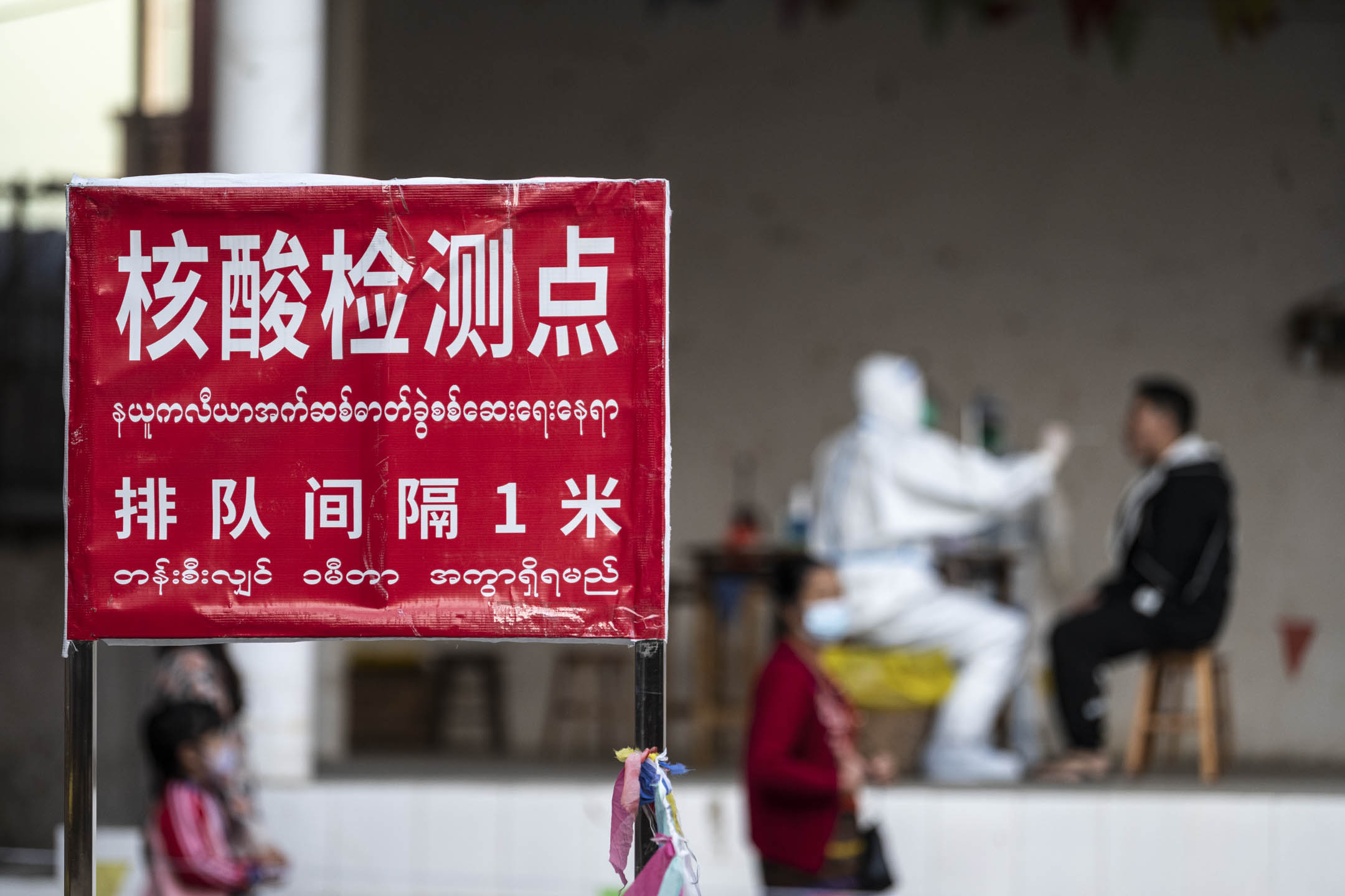 2022年2月24日,中国云南瑞丽市,一名医护人员准备从一名居民身上采集拭子样本,进行 COVID-19 核酸检测。摄:VCG/VCG via Getty Images