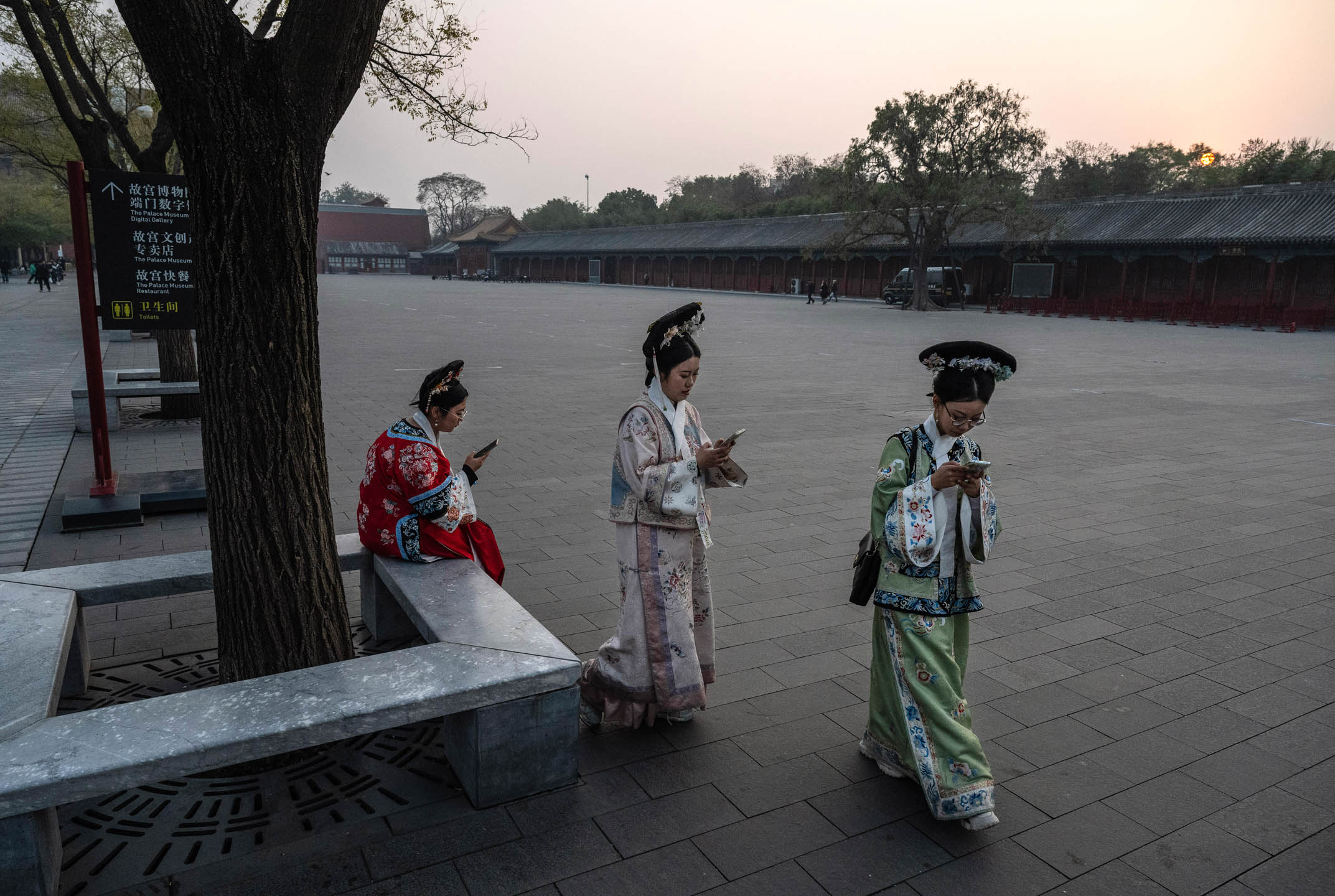 2023年11月21日,中国北京,游客身穿传统汉服看手机。摄:Kevin Frayer/Getty Images