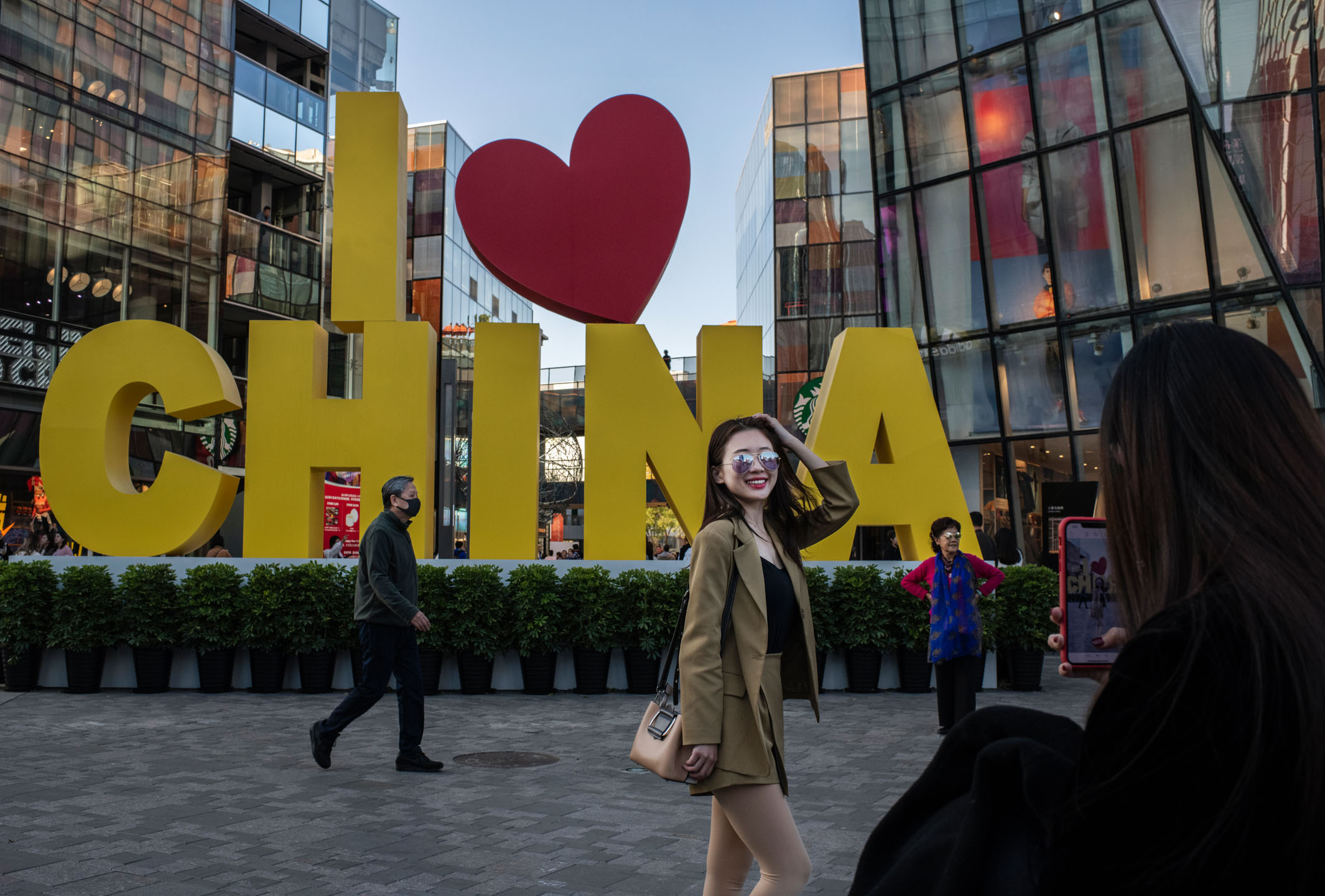 2019年10月31日,中国北京,一名女士在购物中心外拍照。摄:Kevin Frayer/Getty Images