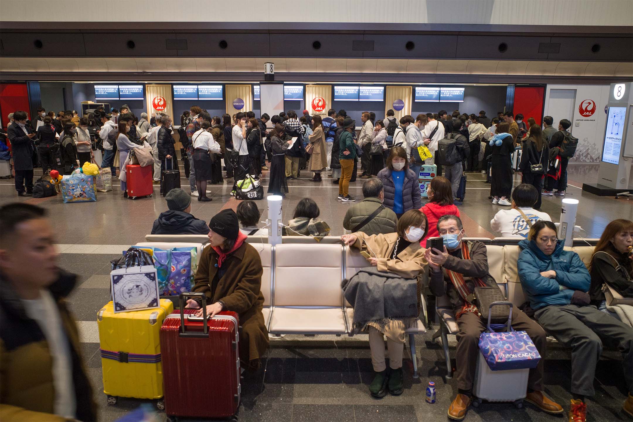 2024年1月2日,日本,因飞机相撞导致航班取消,大批旅客在羽田机场的日本航空公司服务柜台排队。摄:Kentaro Takahashi/Bloomberg via Getty Images