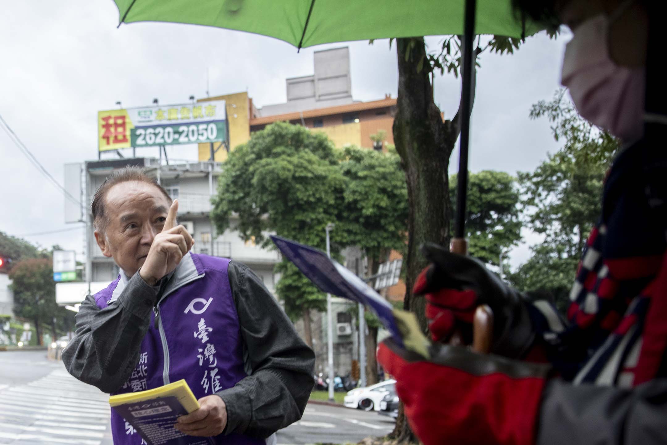 72歲的徐百弟是第一個在台灣參選區域立委的香港人，去年12月一個強烈寒流襲台的一天，徐百弟在雨中派選舉單張。攝：林振東/端傳媒