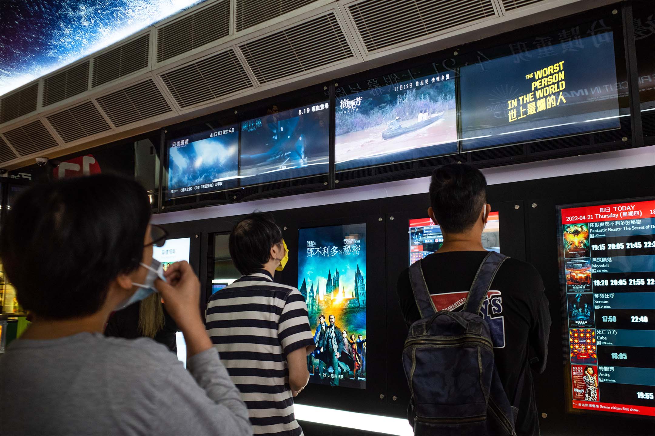 2022年4月1日,香港,市民在電影院外觀看電影預告片。攝:Bertha Wang/Bloomberg via Getty Images