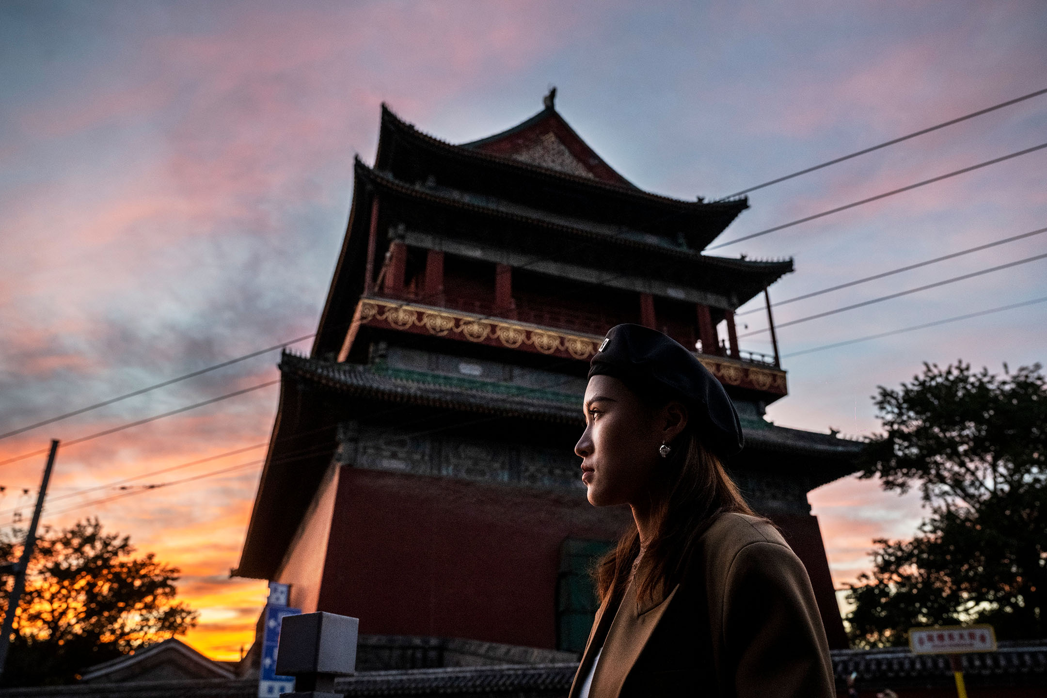 2021年10月10日,中国北京,日落时分,一名女士站在鼓楼附近。摄:Kevin Frayer/Getty Images