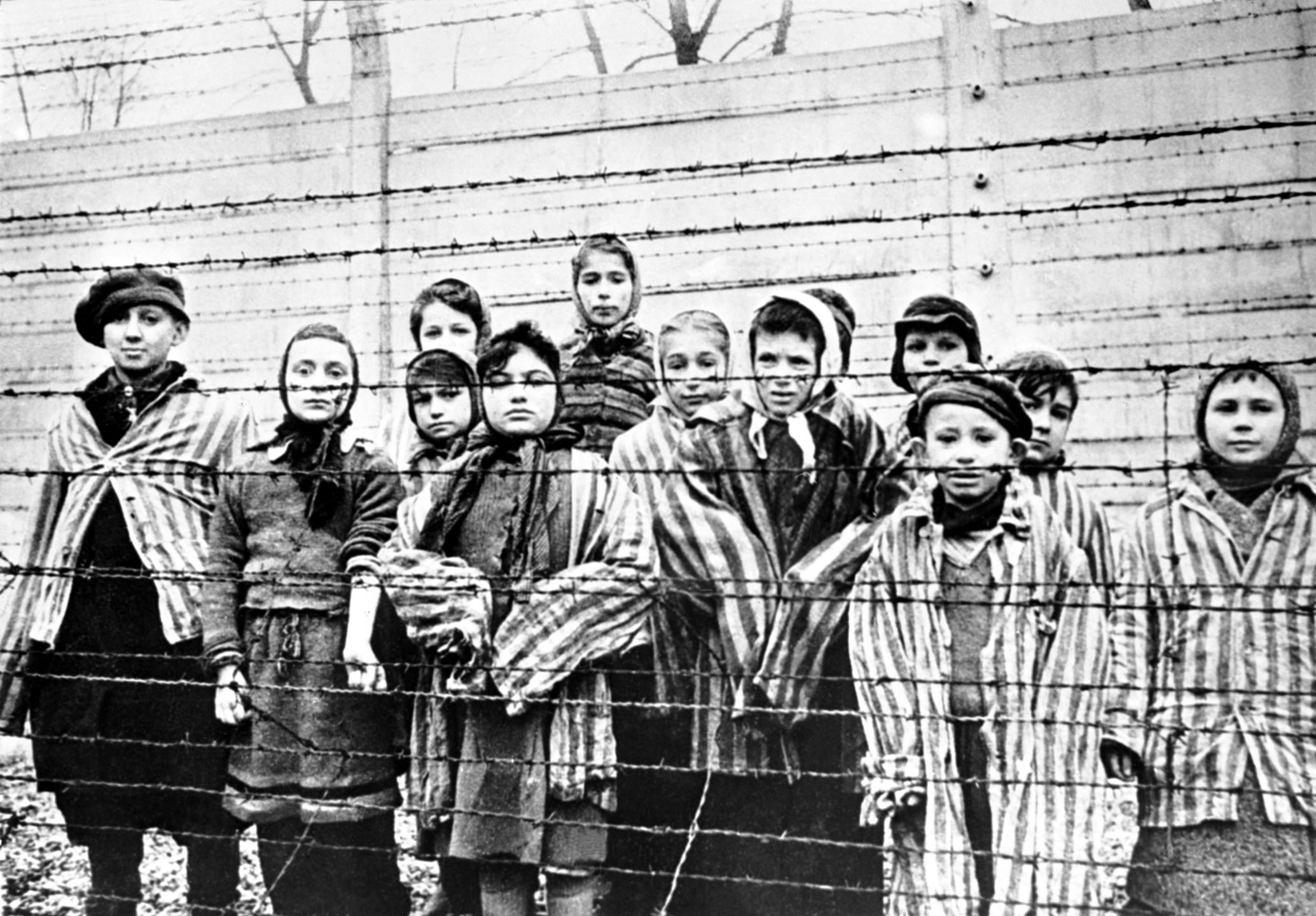 1945年1月27日,纳粹集中营的铁丝网围栏后,一群儿童幸存者。摄:Alexander Vorontsov/Galerie Bilderwelt/Getty Images