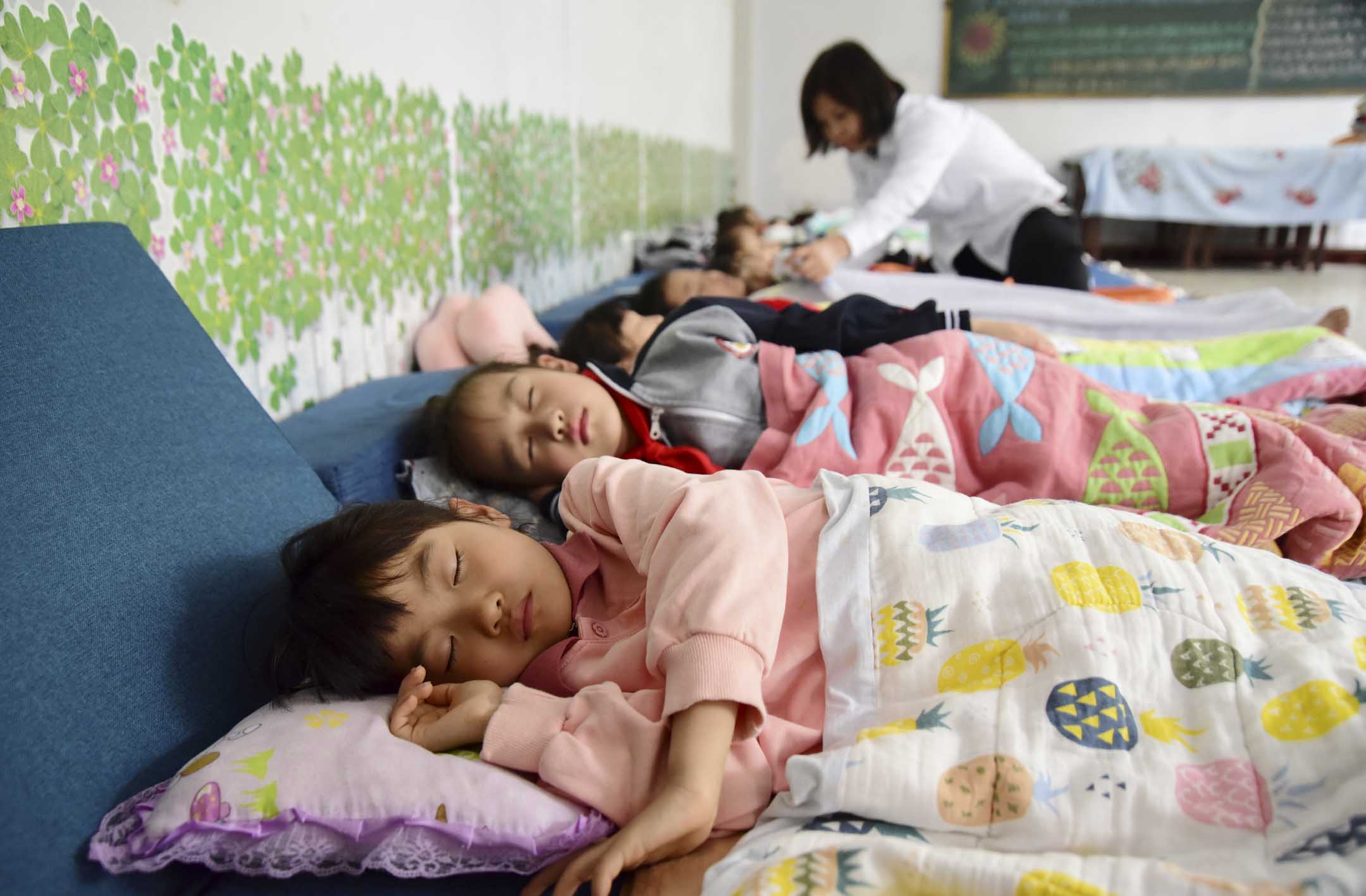 2023年5月29日,中国河北邯郸市,一位老师在午休期间照顾小学生。摄:Hao Qunying / CFOTO/Future Publishing via Getty Images