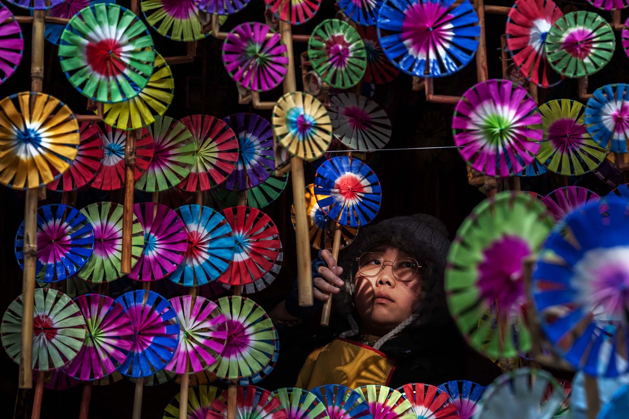 2024年2月13日,中國北京,一名女士正在看擺滿風車的攤位。攝:Kevin Frayer/Getty Images
