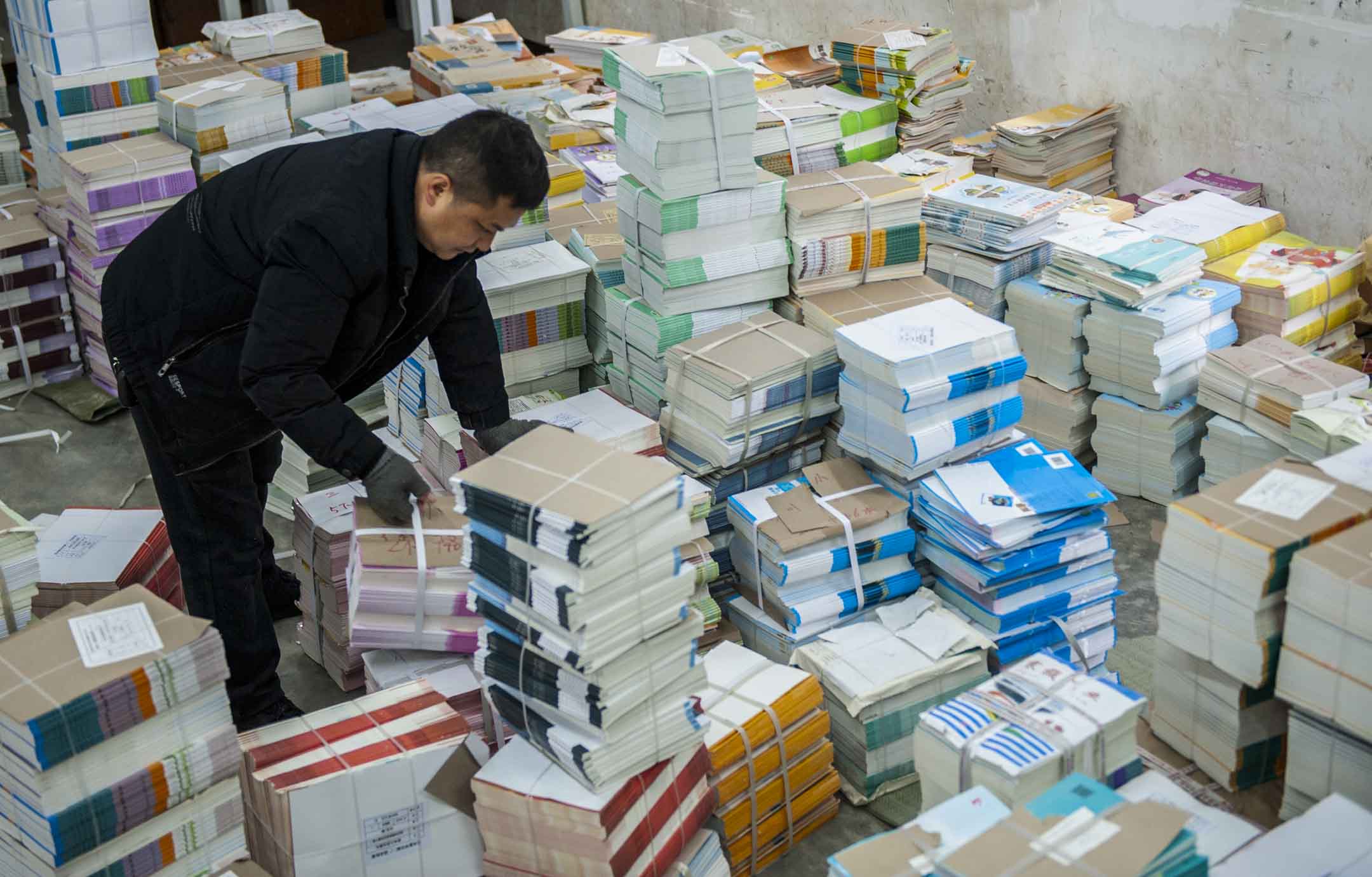 2023年2月13日,中国贵州一间小学的老师正在清点新学期的教科书。摄:CFOTO/Future Publishing via Getty Images