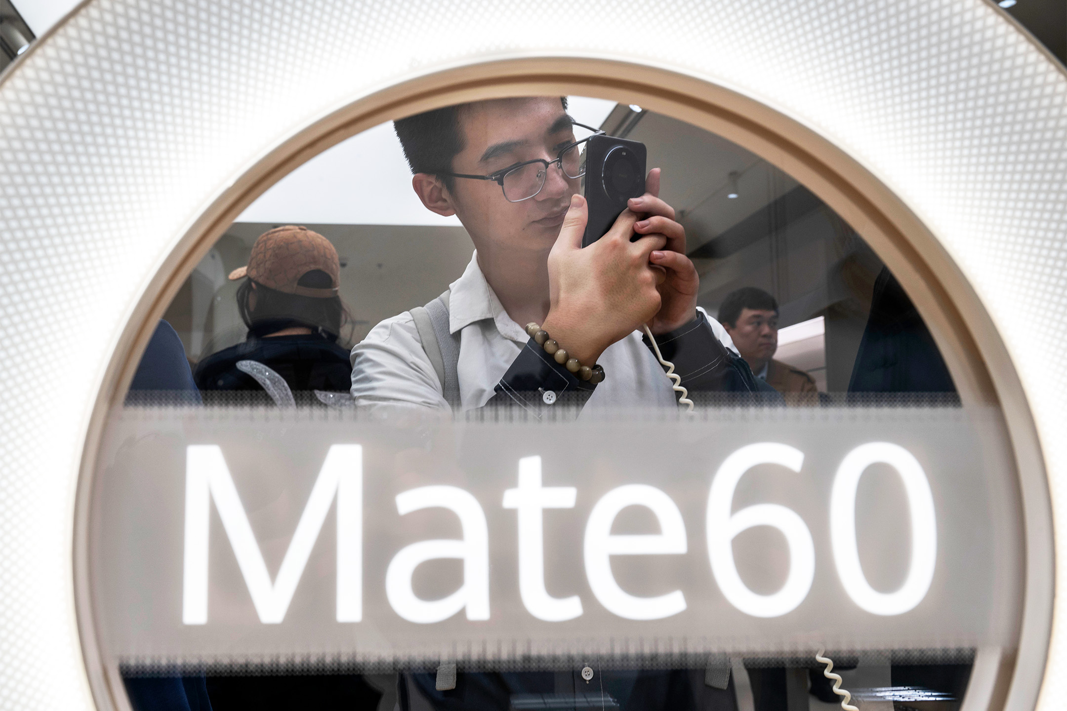 2023年9月25日,中國北京,一名顧客在華為旗艦店看新推出的 Mate 60 智能手機。攝:Kevin Frayer/Getty Images