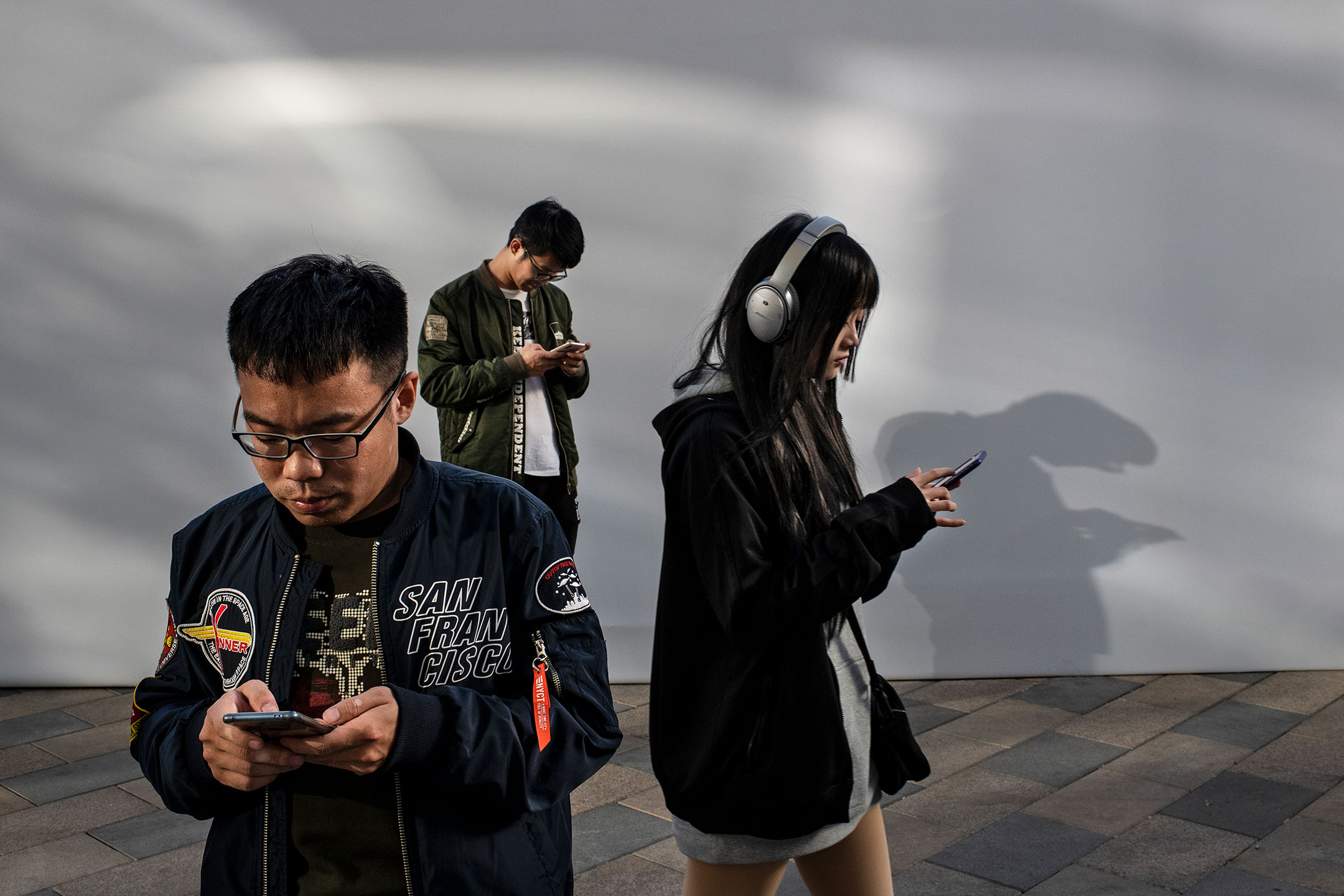 2019年10月31日,中国北京,市民在购物中心看手机。摄:Kevin Frayer/Getty Images