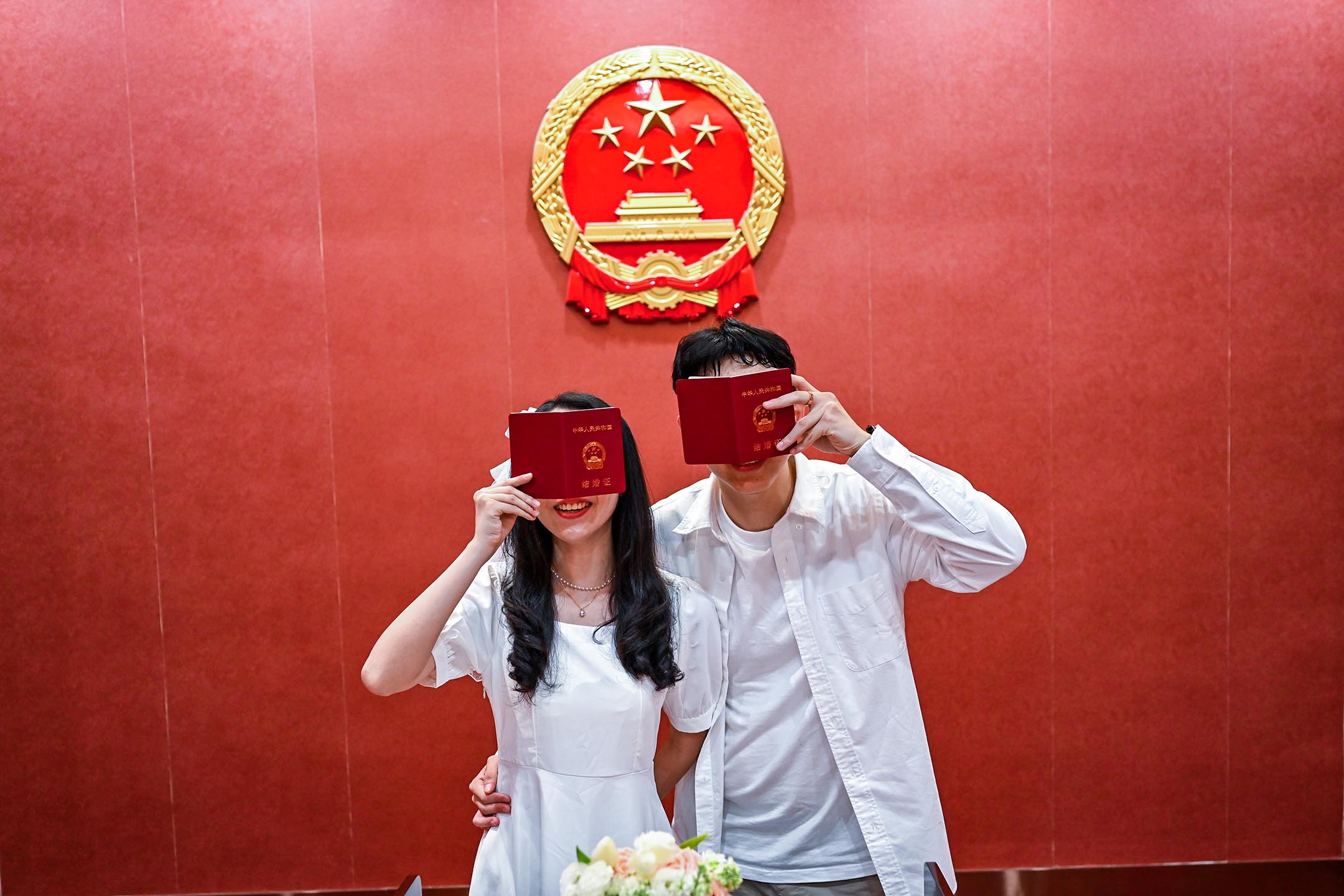 2023年5月20日,一对新婚夫妇在中国福建省泉州婚姻登记中心拿著结婚证书摆拍。摄:Xie Mingfei/VCG via Getty Images