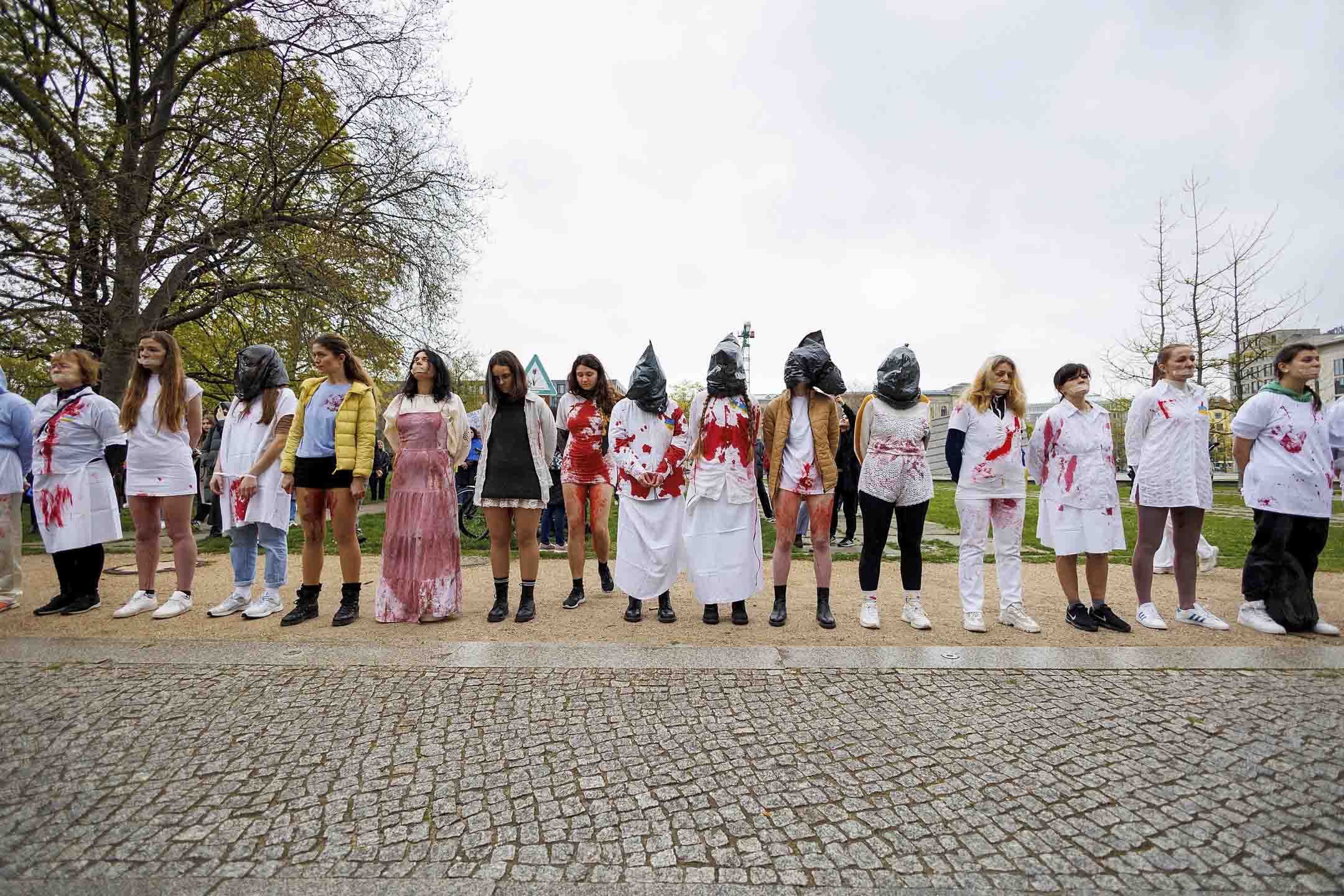 2022年4月21日,德國柏林,女性身穿沾有人造血的白衣,手牽手抗議俄烏戰爭期間俄羅斯針對女性的暴力行為。攝:Carsten Koall/picture-alliance/dpa/AP/達志影像
