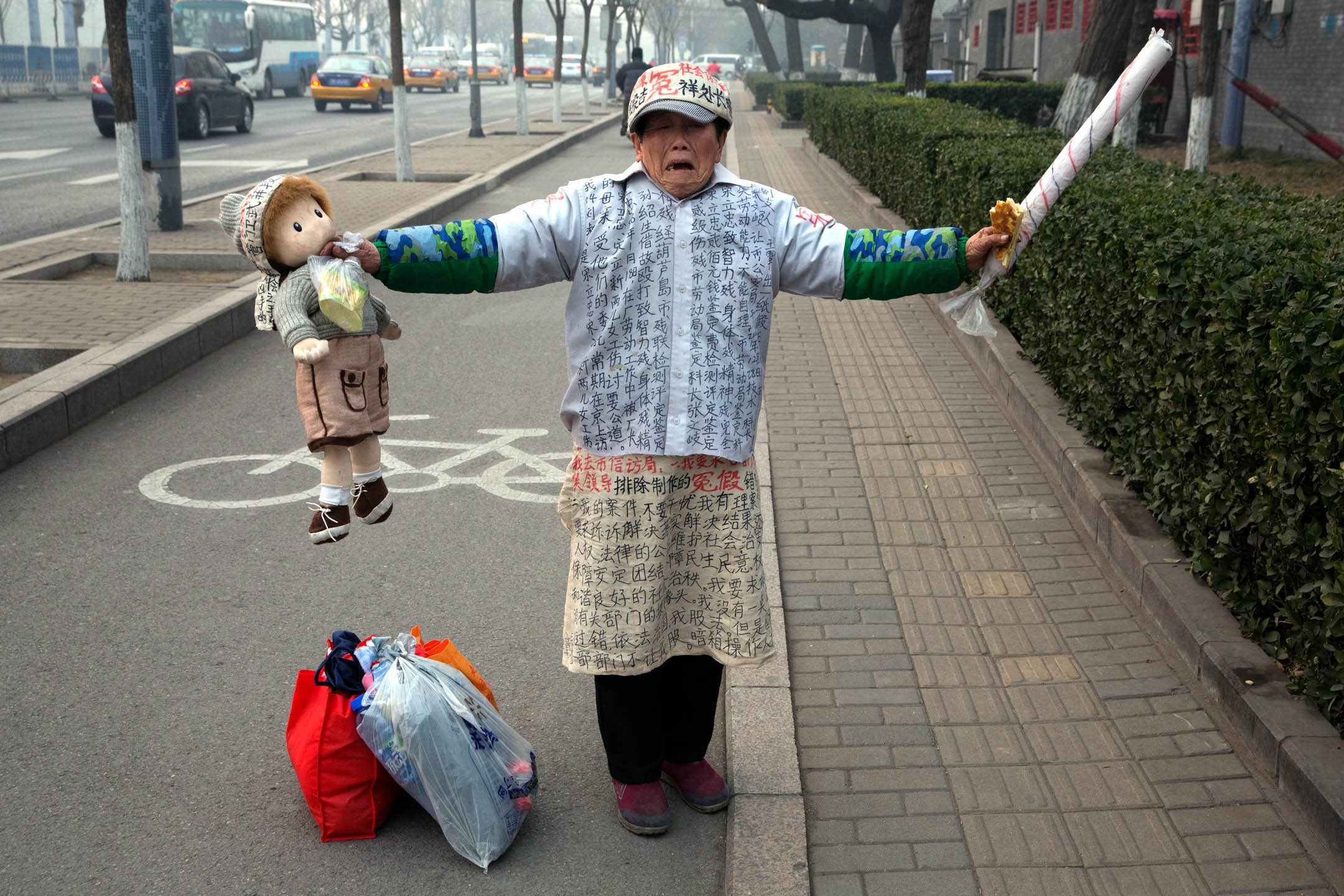 2015年12月22日,中国北京,一名男士身穿写满抗议字句的衣服站在街道上。摄:Ng Han Guan/AP/达志影像