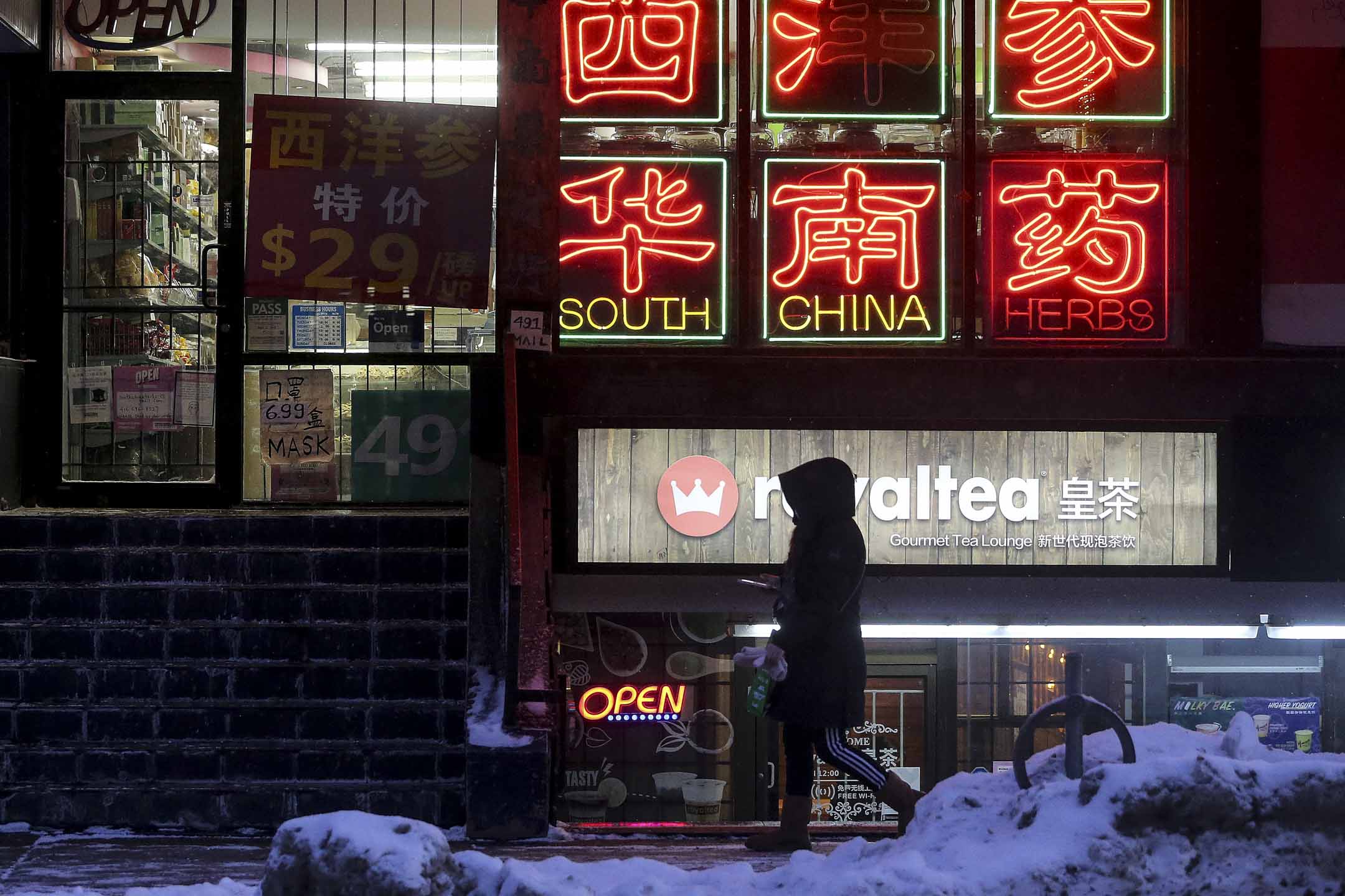 多倫多唐人街晚上一位女士在商店前經過。攝:Steve Russell/Toronto Star via Getty Images