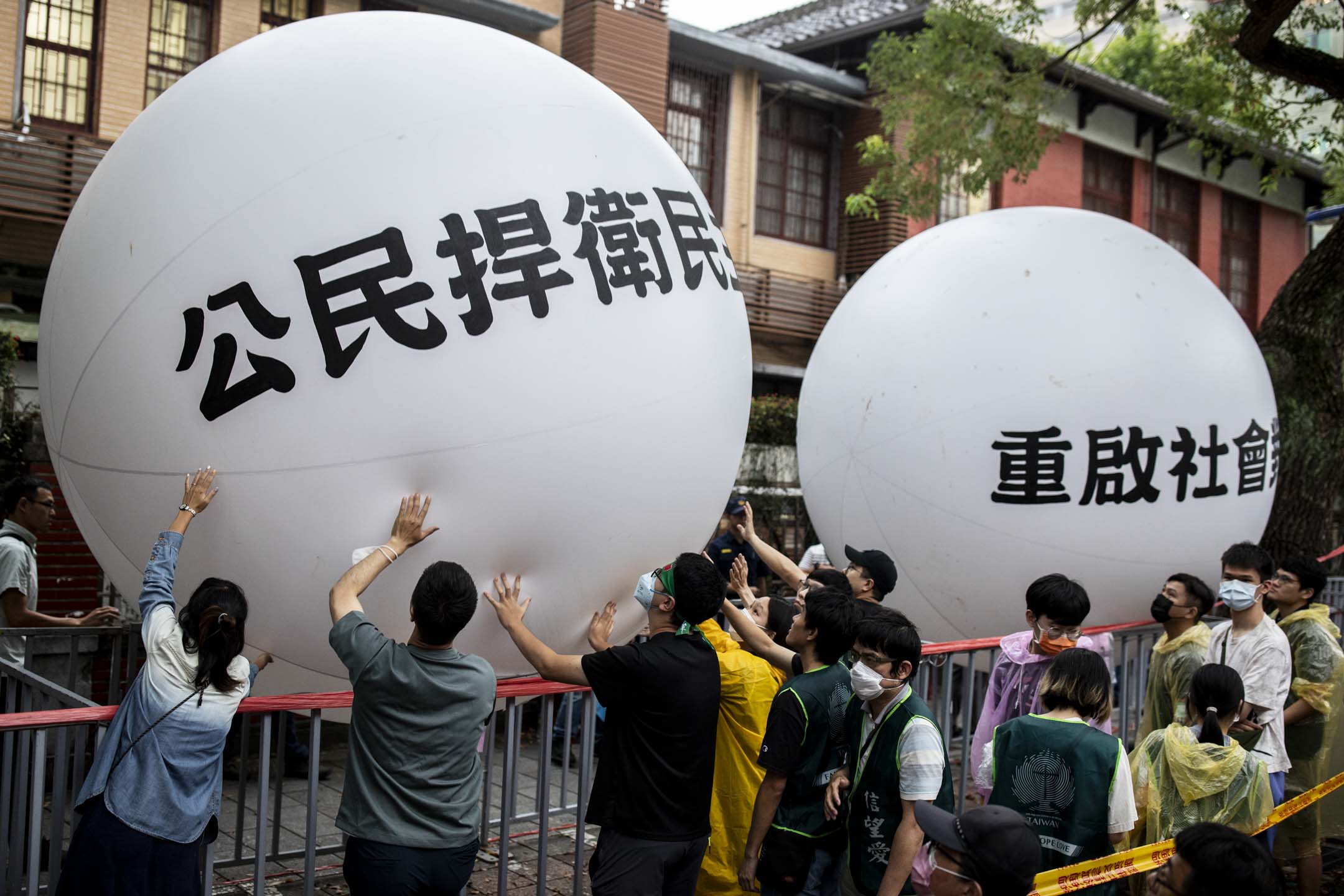 2024年5月28日,台北,立法院進行國會改革法案審議,立法院外有民衆集會,抗議民眾把寫著「公民捍衛民主」、「重啟社會對話」的大型氣球,接力傳遞到立法院前,表達這次行動訴求。攝:林振東/端傳媒