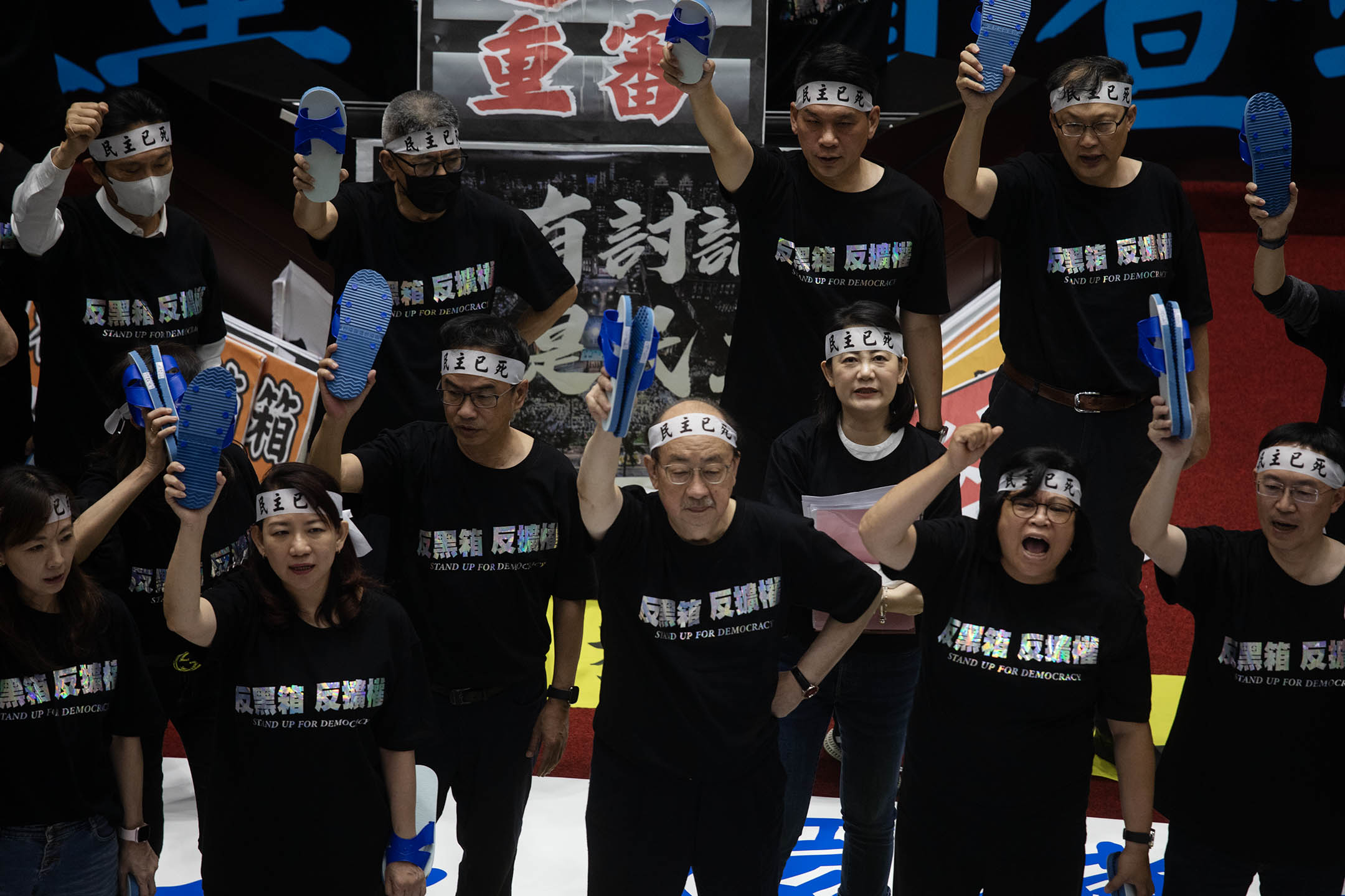 2024年5月24日,台北,立法院繼續處理藍白國會改革提案,民進黨立委舉起藍白色的拖鞋。攝:陳焯煇/端傳媒
