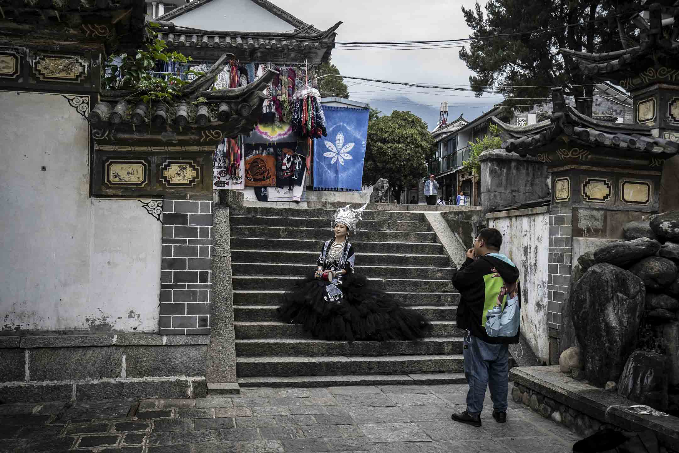 2022年9月6日,中国云南大理,一名身著各种少数民族服饰的游客在摆姿势拍照。摄:Qilai Shen/Bloomberg via Getty Images