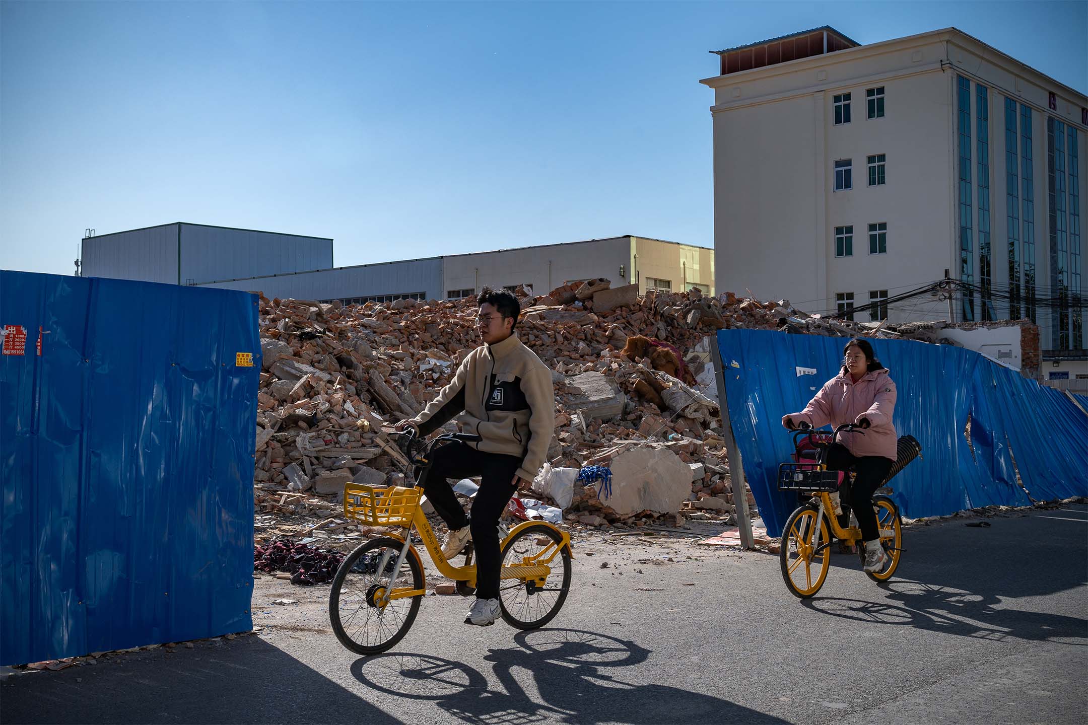 2023年11月17日,中國北京,人們騎單車經過被拆除的建築物。攝:Andrea Verdelli/Bloomberg via Getty Images