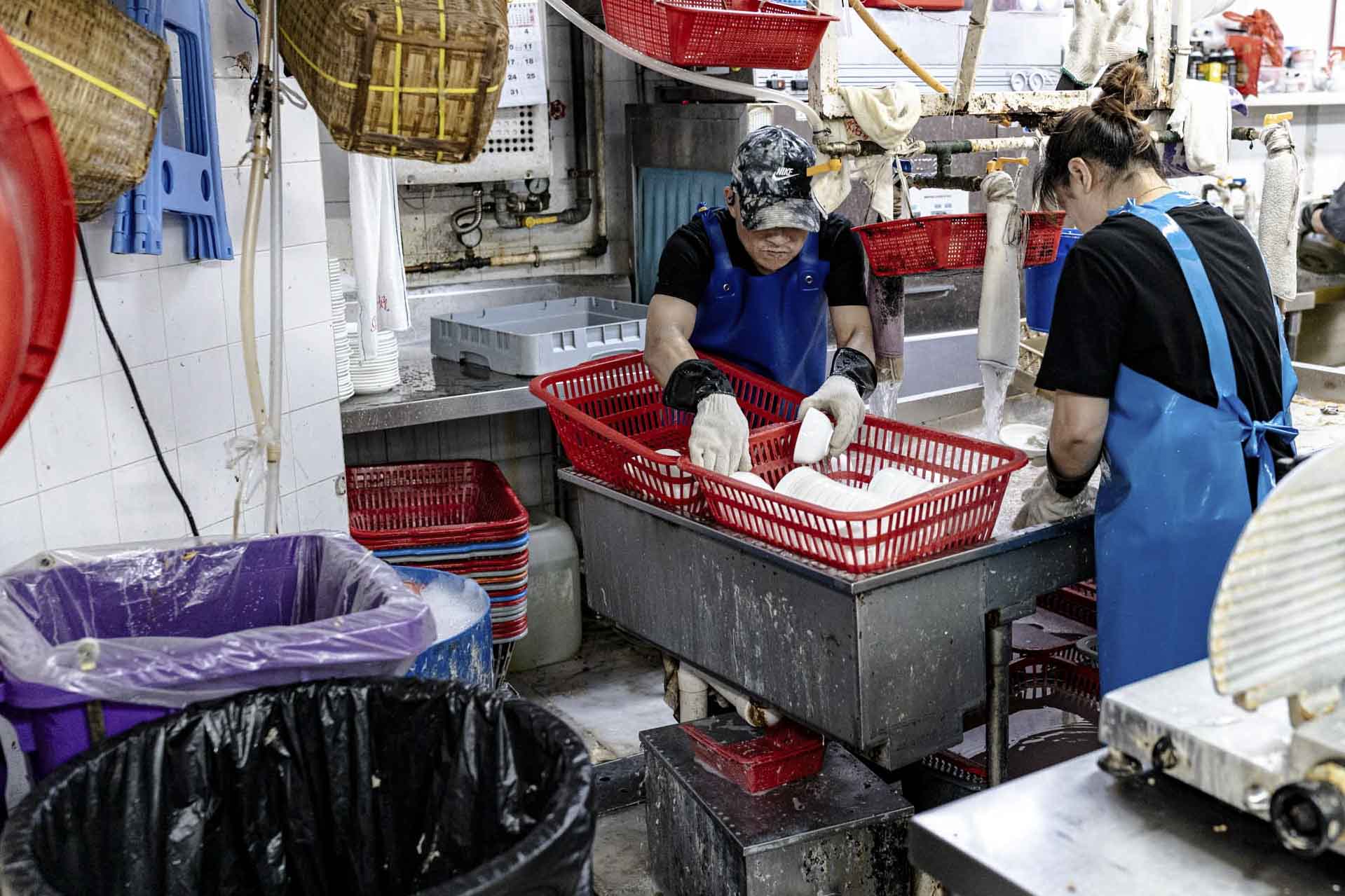 新光宴會廳的員工正在廚房洗碗,以及將廚餘放在紫色廚餘桶內。攝:Ryan Lai/端傳媒
