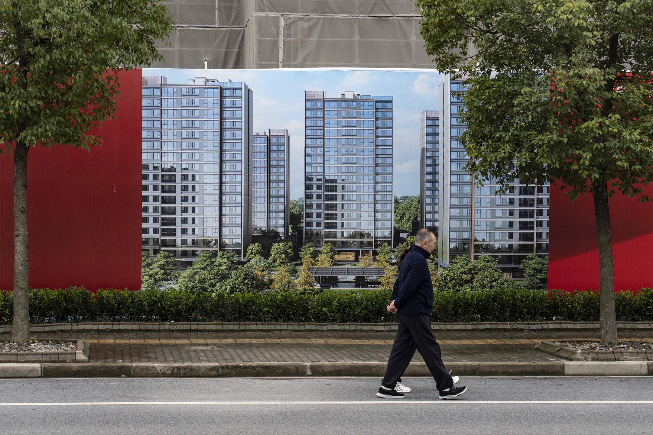 2024年3月19日,中國上海,一名男子在住宅項目開發的廣告牌前經過。攝:Qilai Shen/Bloomberg via Getty Images