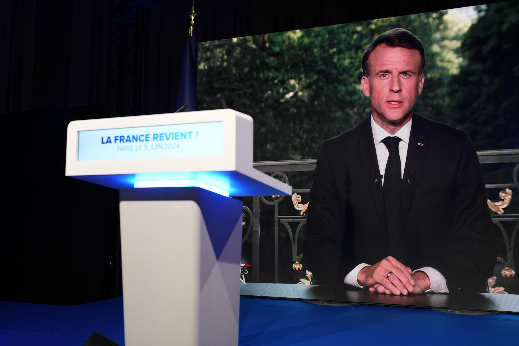2024年6月9日,法國總統馬克龍 (Emmanuel Macron) 在歐盟投票失敗後解散國民議會並召開大選,其直播畫面出現在法國極右翼國家集會黨選舉之夜的電視螢幕上。攝:Lewis Joly /AP/達志影像