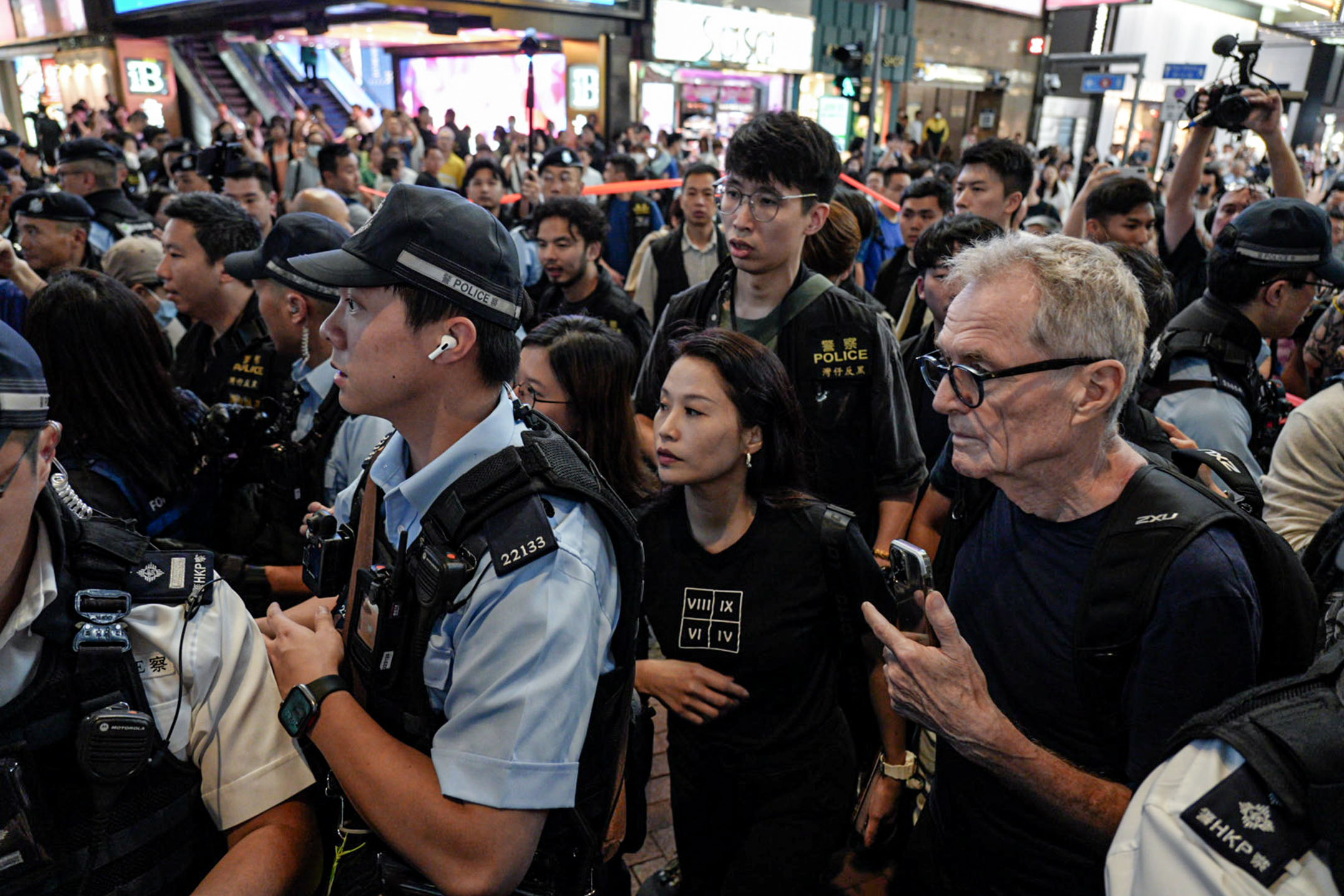2024年6月4日,一名女士身穿印有羅馬數字的衣服,被警方包圍後帶上警車。攝:Ryan Lai/端傳媒