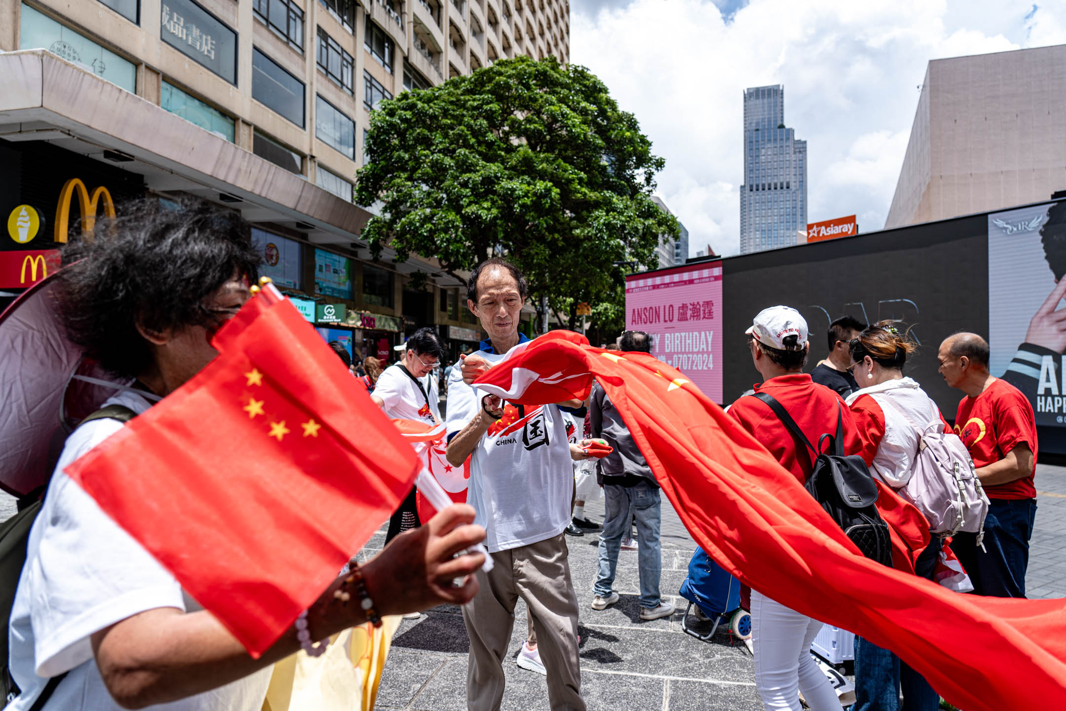 2024年7月1日，有市民在尖沙咀天星碼頭外揮動國旗與區旗，慶祝回歸27週年。攝：Ryan Lai/端傳媒