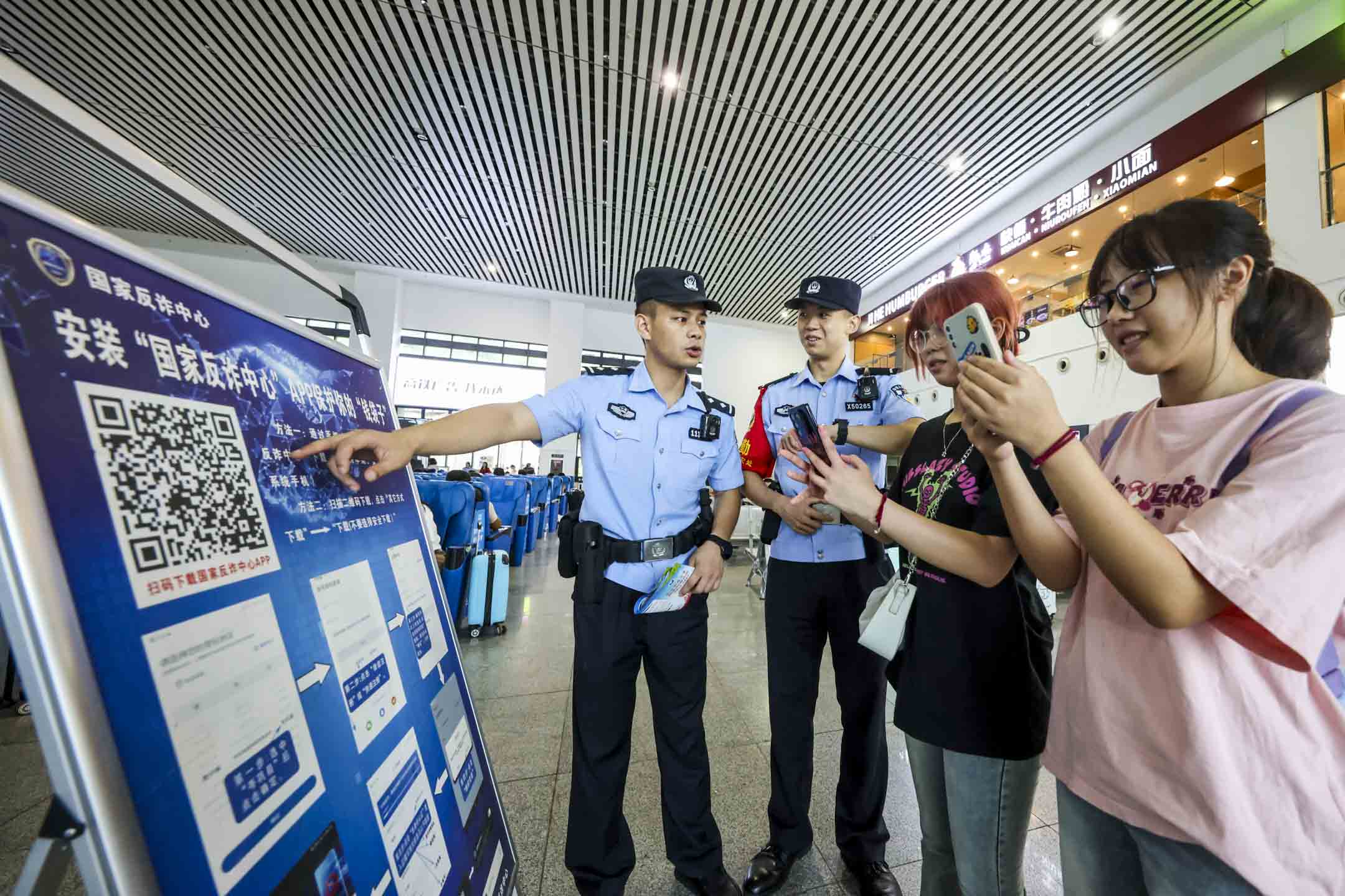 2023年8月24日，中國貴州，鐵路警察引導乘客下載「反詐APP」。攝：CFOTO/Future Publishing via Getty Images