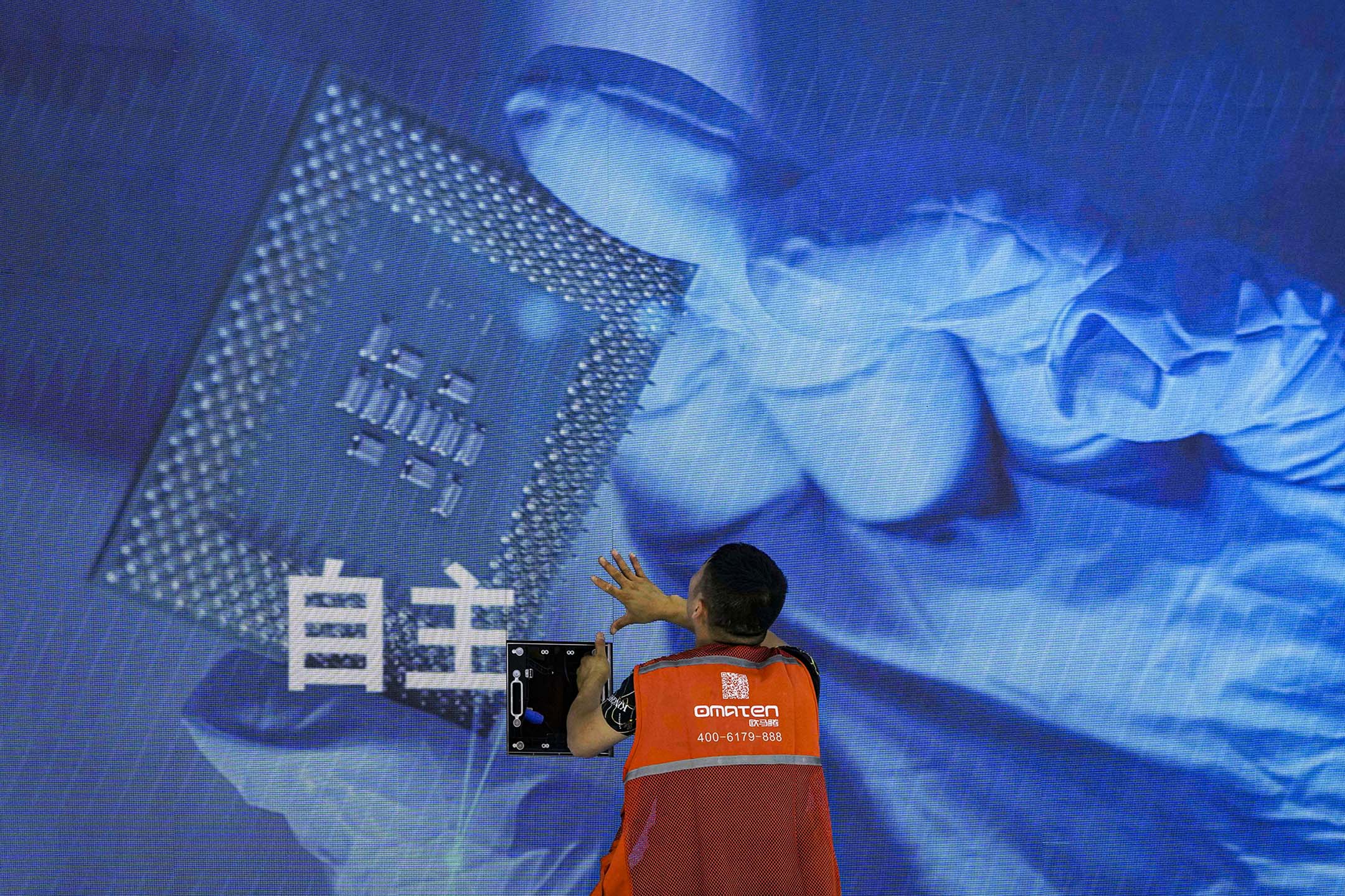 2023年7月5日,上海舉行的世界人工智慧大會期間,一名工人在參展的攤位上檢查顯示著電腦晶片的螢幕。攝:Ng Han Guan/AP/達志影像