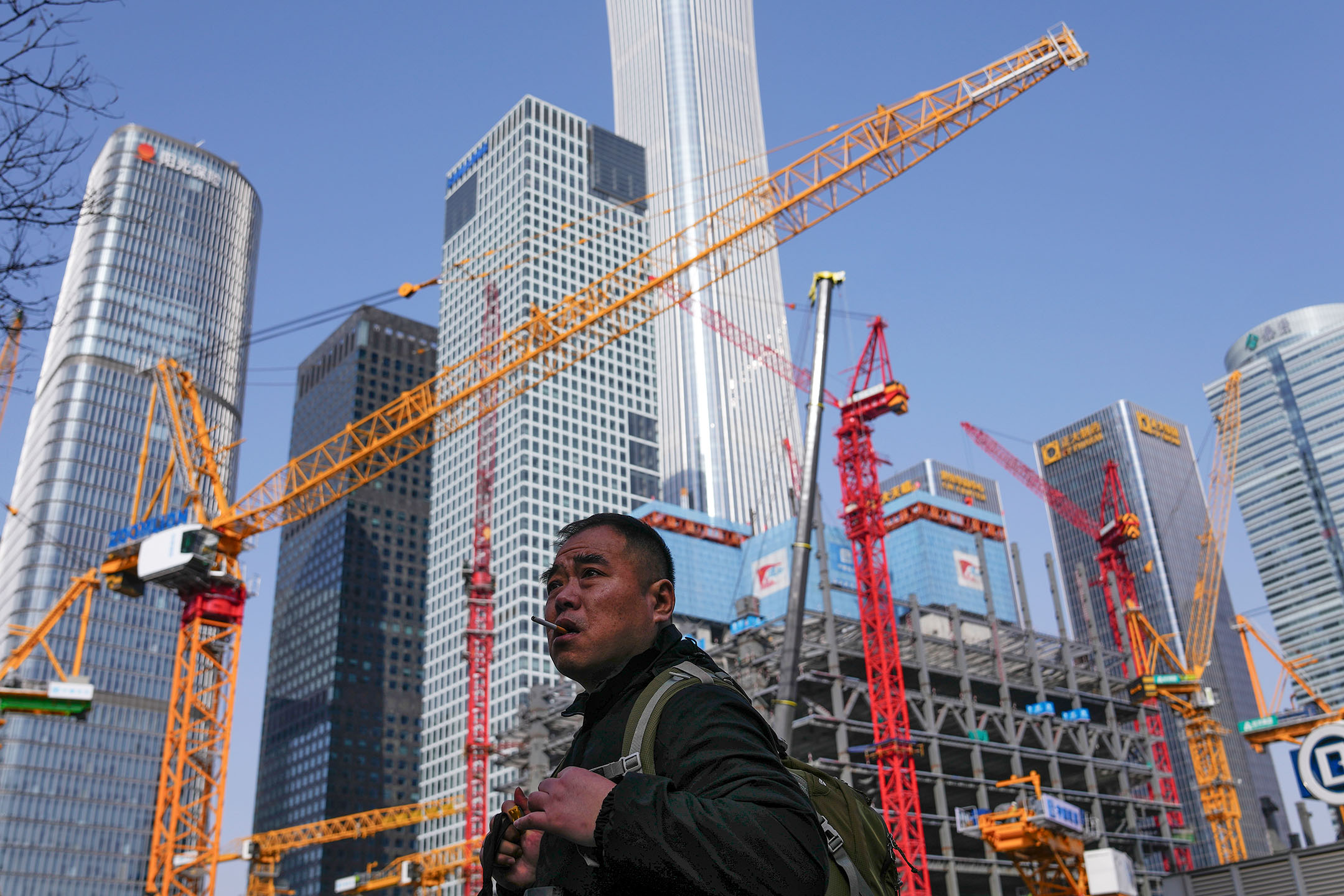2024年3月2日,中国北京,一名男子经过中央商务区附近的建筑工地。摄:Andy Wong/AP/达志影像