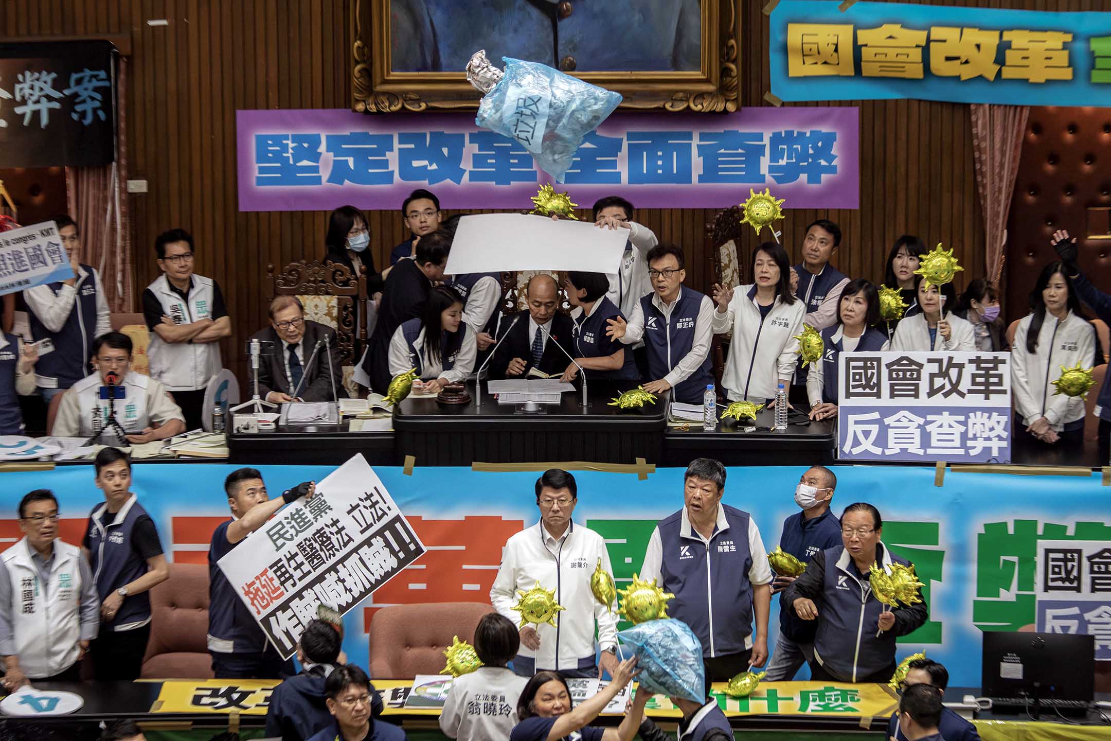 2024年5月28日,台北,立法院進行國會改革法案審議,立法院内民進黨立委向主席台掉垃圾,國民黨立委用看板阻擋保護立法院長韓國瑜。攝:陳焯煇/端傳媒