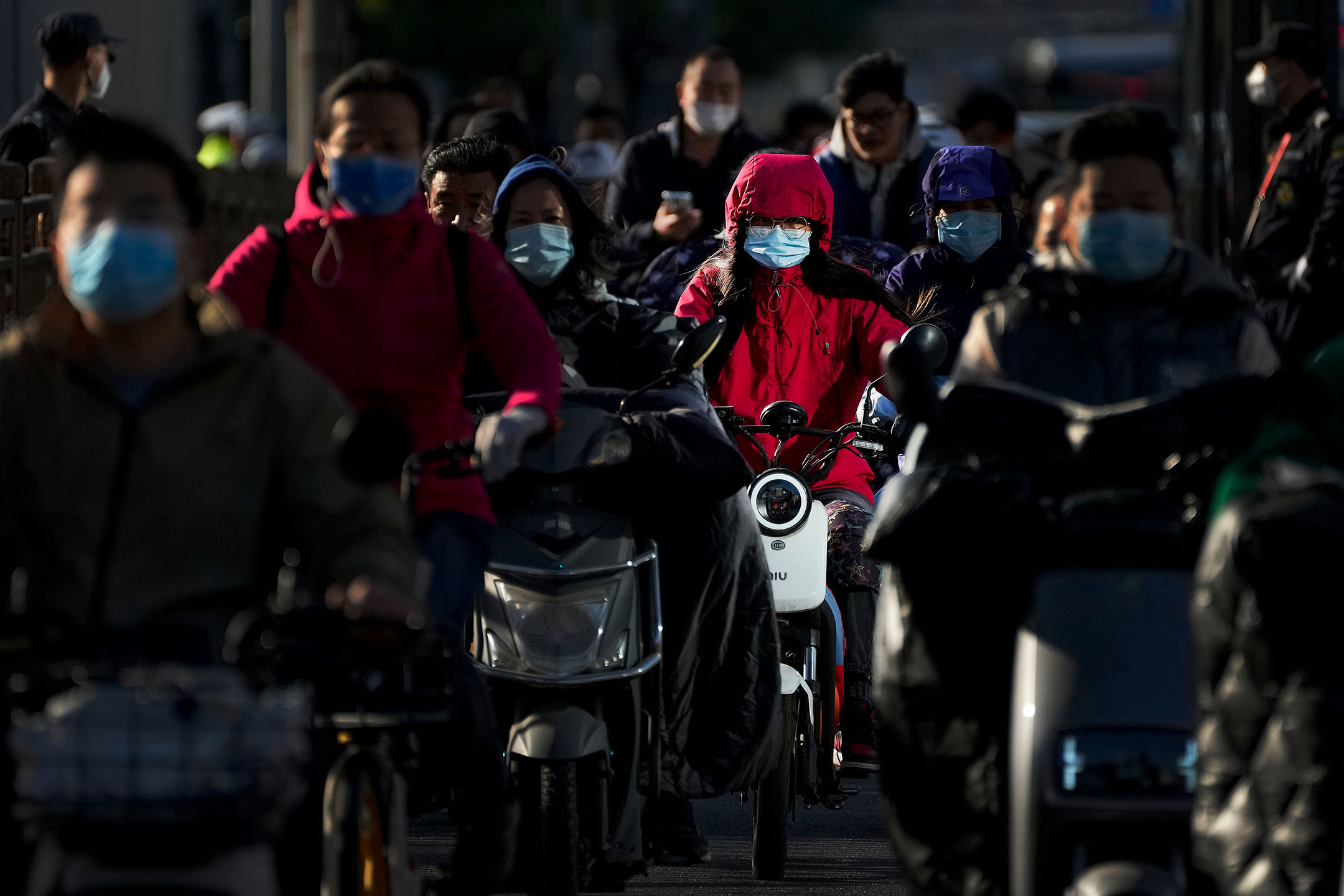 2022年10月16日,中国北京,人们在街上骑着电动车。摄:Andy Wong/AP/达志影像