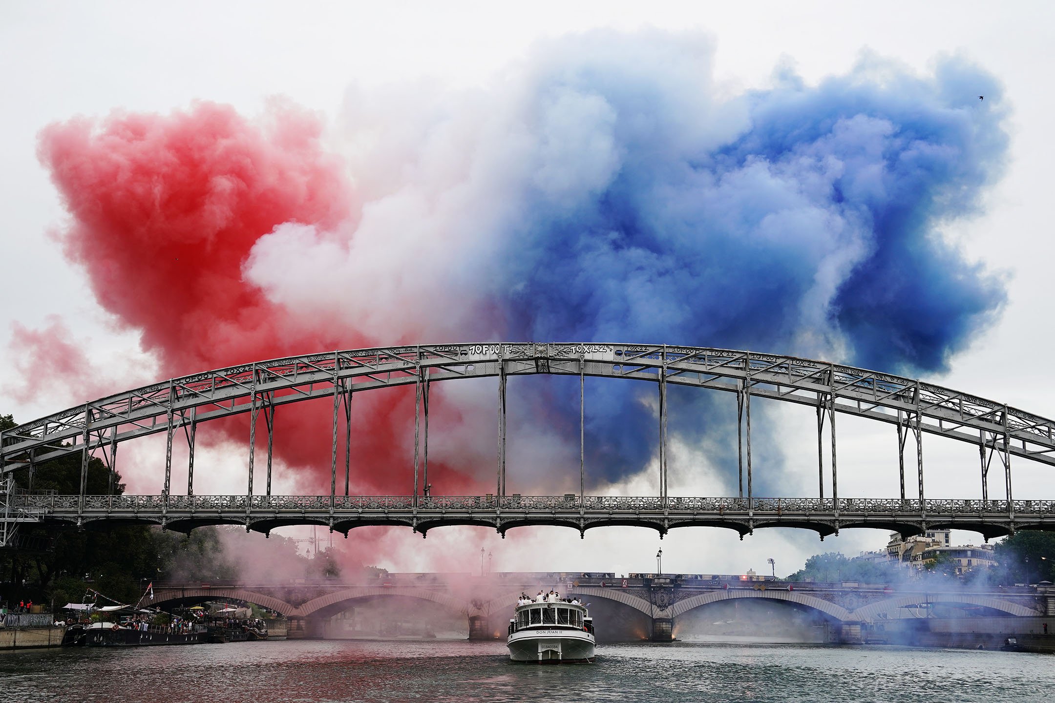 2024年7月26日,法国巴黎,桥上冒出法国国旗颜色的烟雾。摄:David Burnett/IOC via Getty Images
