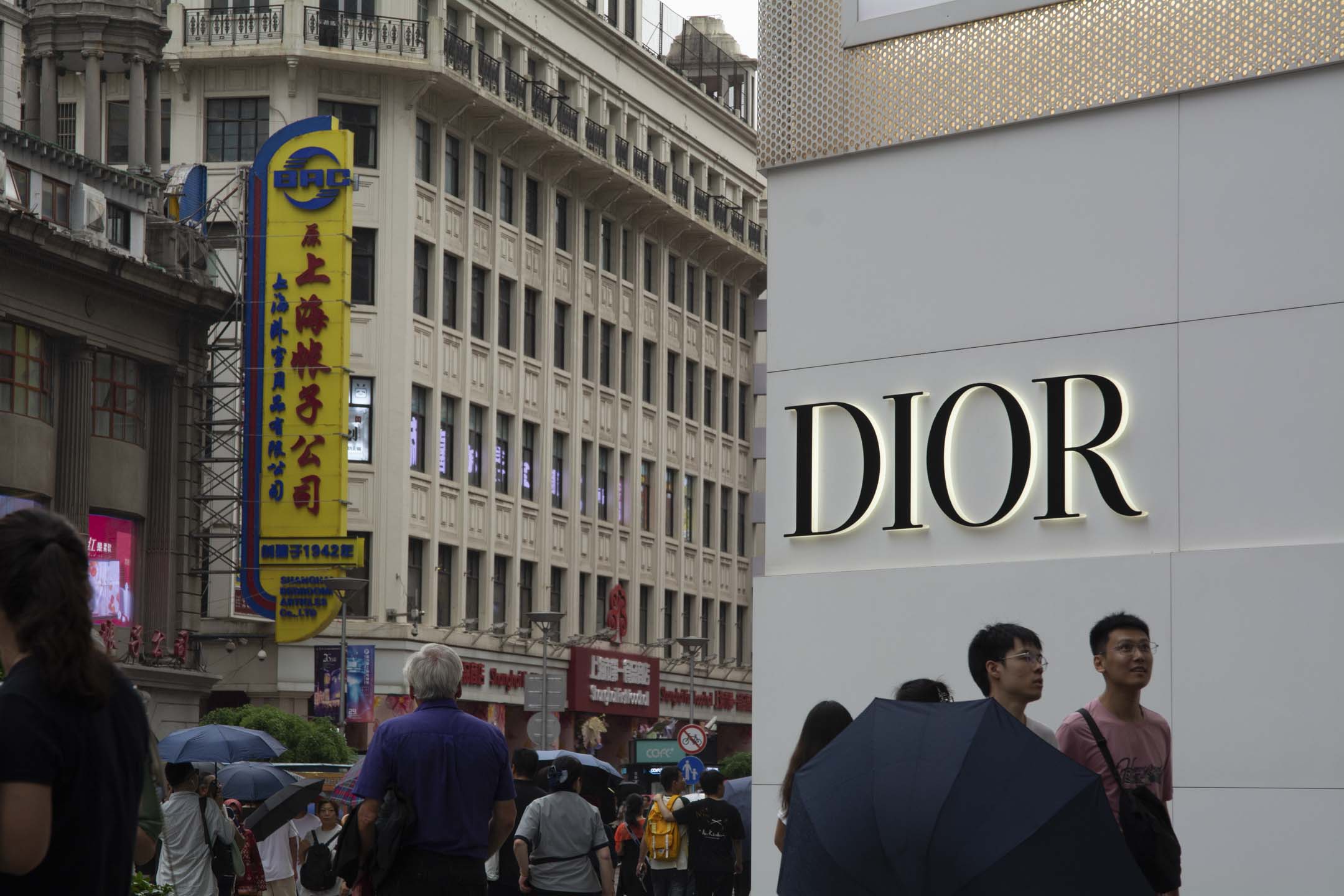 2024年6月22日,游客走过中国上海南京东路中心购物区的 Dior 店。摄:Ying Tang/NurPhoto via Getty Images