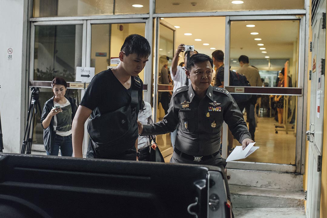 马来西亚死者的儿子(左)由泰国警方发言人Pongsapat Pongcharoen陪同下认领母亲遗体。摄 : Anthony Kwan/端传媒