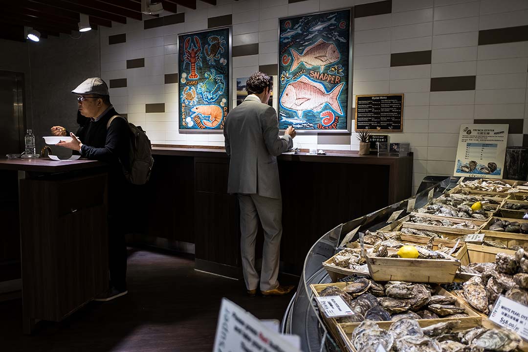 顧客在超市內品嚐來自世界各地的海鮮，當中包括日本福岡海域的生蠔。攝：Billy H.C. Kwok/端傳媒