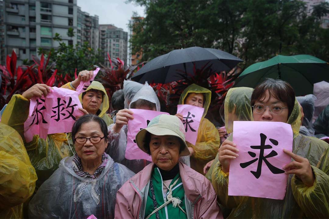 示威者冒雨在场外抗议,现场有警察维持秩序。摄:Billy H.C. Kwok/端传媒