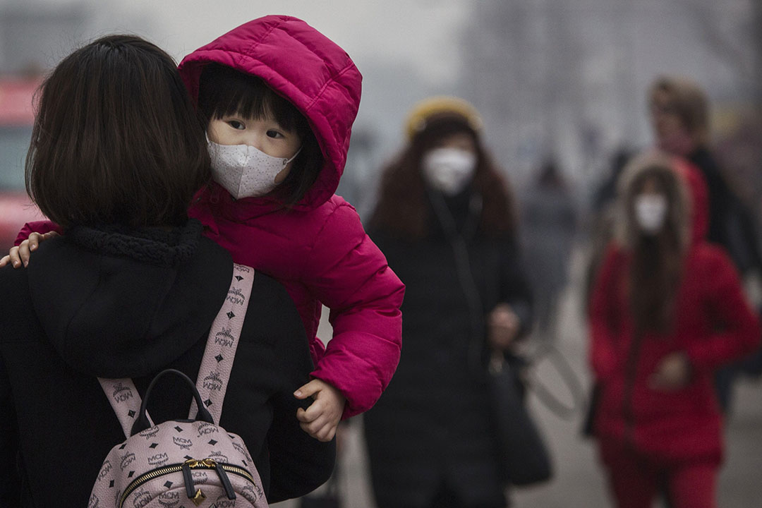 2015年12月8日,北京,一名女童在严重雾霾下戴口罩上街。 摄:Kevin Frayer/GETTY