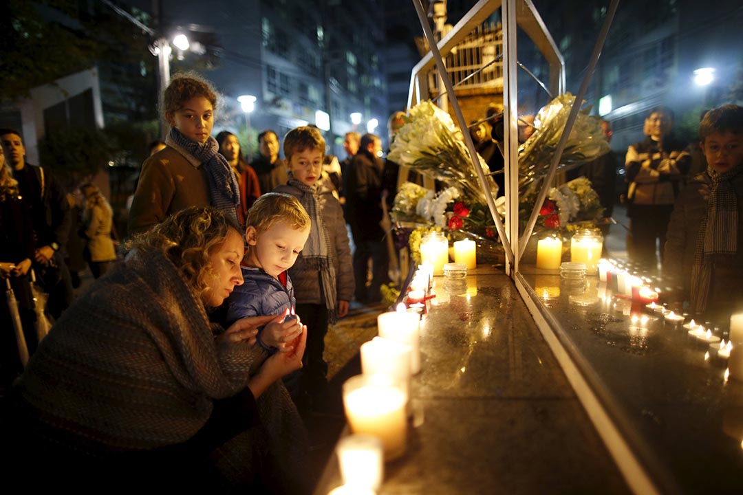 2015年11月14日,韓國首爾一名母親與孩子點起蠟燭悼念巴黎恐怖襲擊的遇難者。攝:Kim Hong-Ji/REUTERS