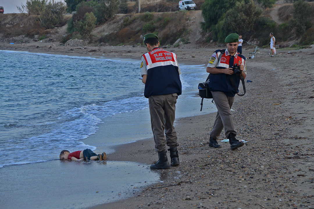 土耳其憲兵在一名溺斃的三歲小童Aylan Kurdi屍體旁調查,Aylan Kurdi一家四口登上偷渡船隻希望前往歐洲生活,不幸在土耳其對出海洋沉沒。Aylan Kurdi和哥哥及母親一同溺斃,當父親前往認屍後向傳媒表示,家人死去令他打消前往歐洲的念頭,準備返回敘利亞。攝:Nilufer Demir/DHA/REUTERS